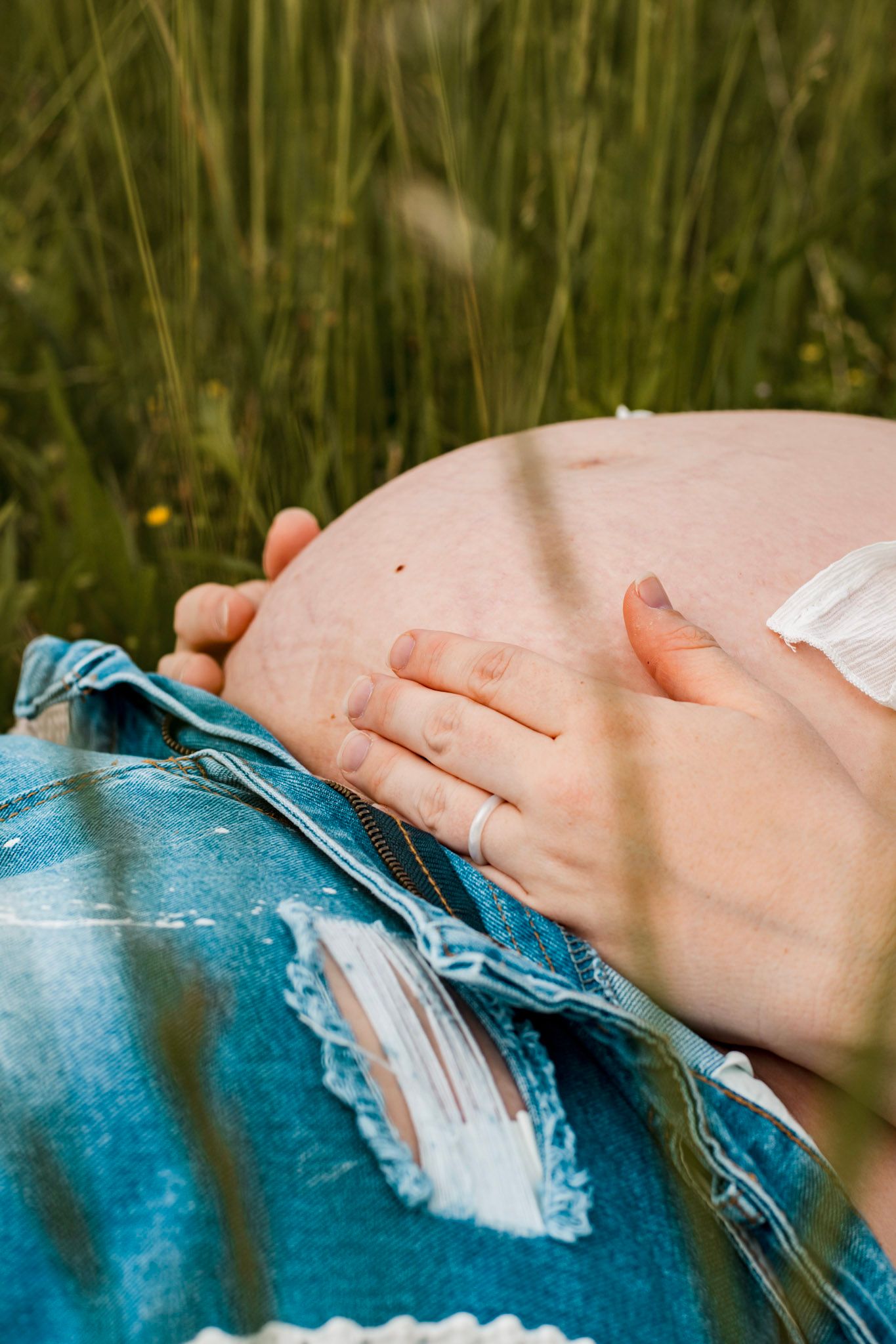 Close-up of hands resting on pregnant belly for a maternity session in natural outdoor lighting at Vaughter's Farm in Lithonia, GA