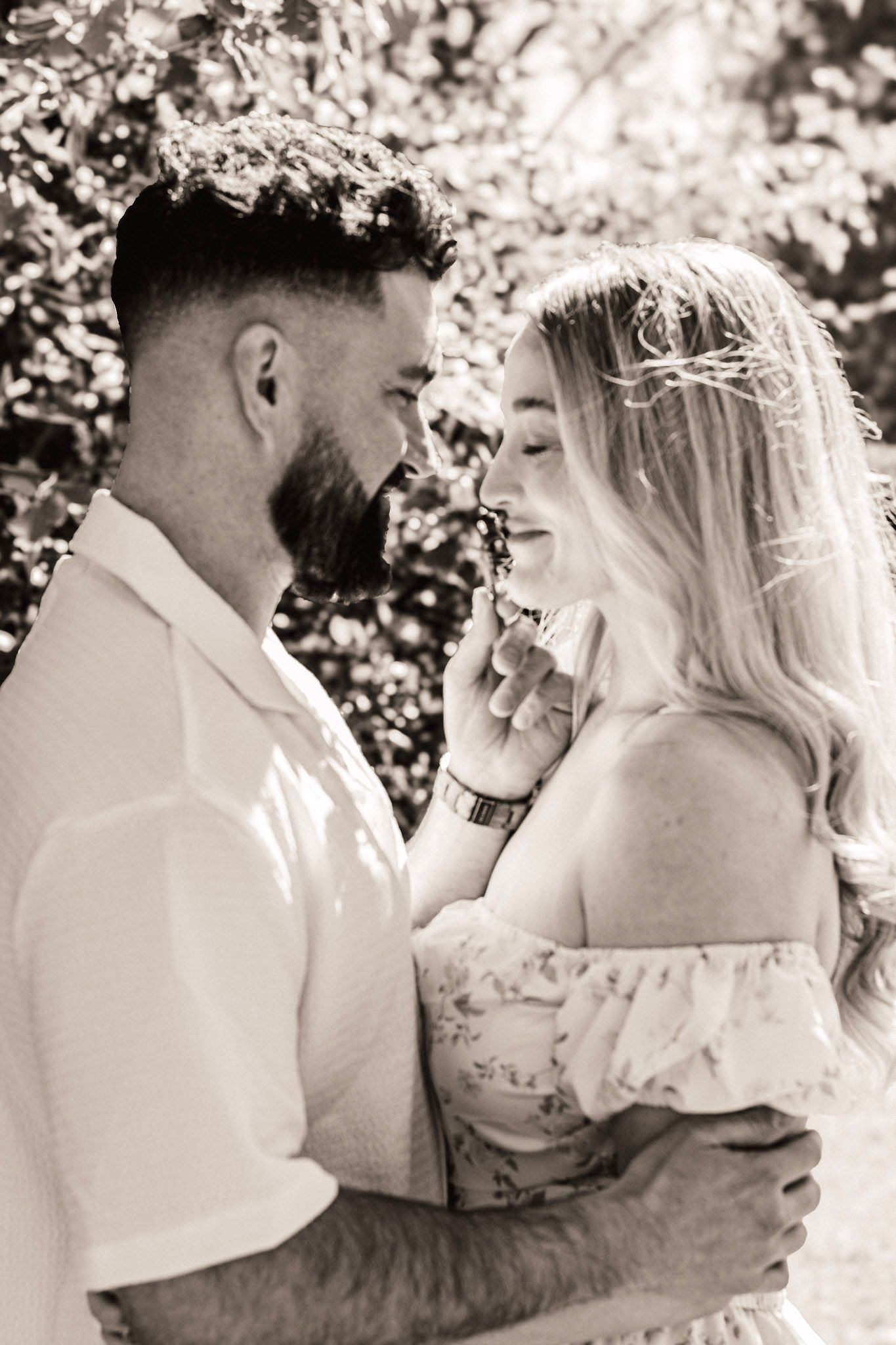 A black and white photo of a couple at an engagement session along a wooded path at Piedmont park in Atlanta, Georgia.