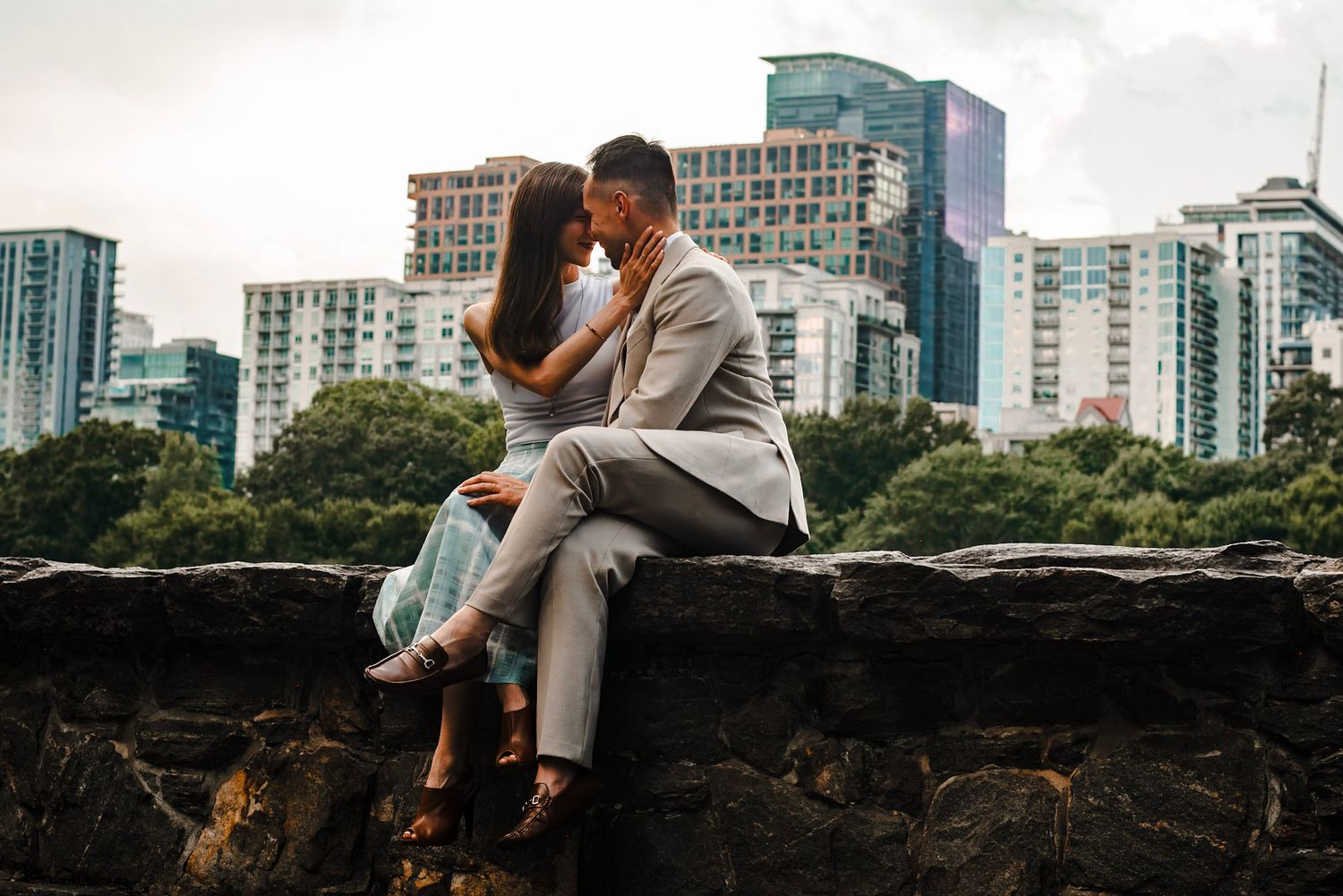 A couple shares a romantic kiss on stairs overlooking Atlanta skyline at Piedmont park in Atlanta, Georgia.