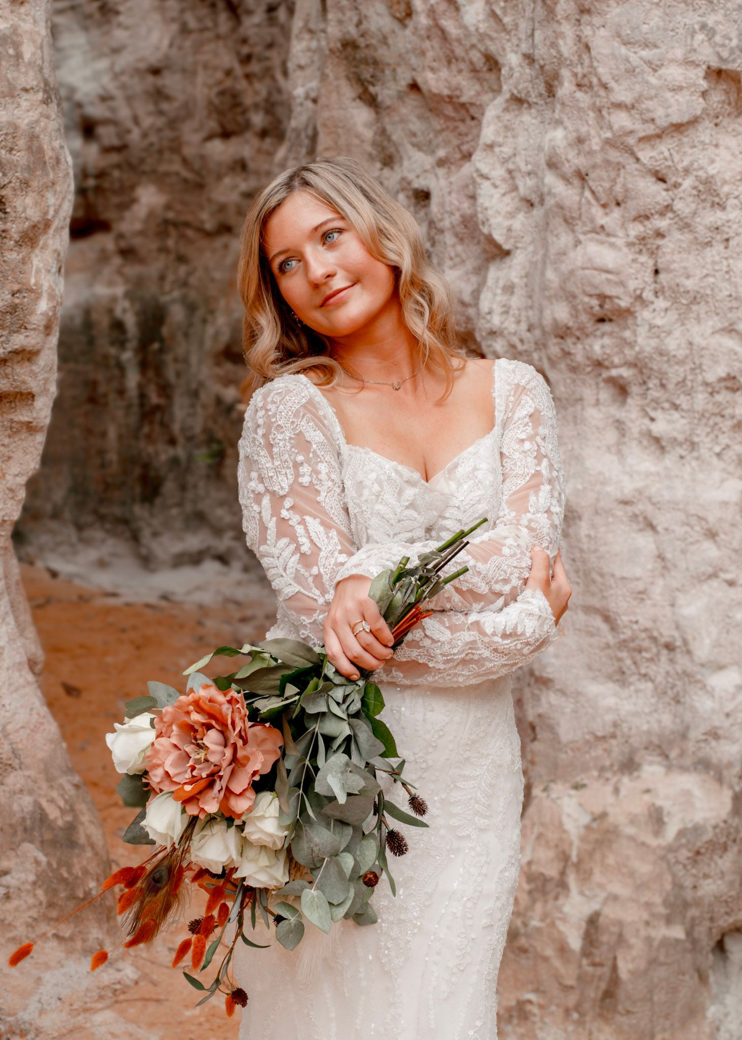 A bride in a lace wedding dress holds a bouquet with flowers and eucalyptus at Providence Canyon in Lumpkin, Georgia