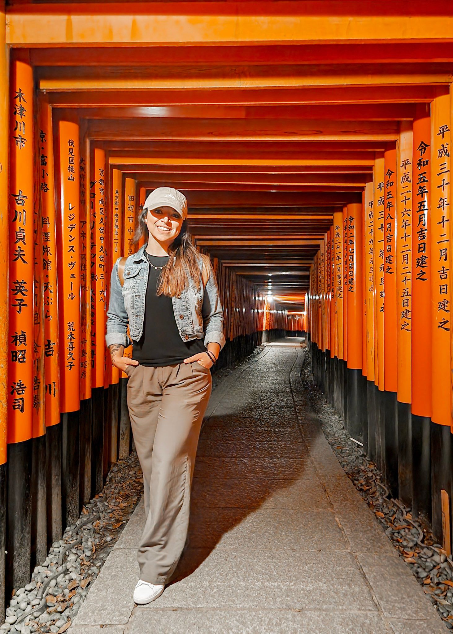 Emily Hall in torii gates forming a tunnel pathway at Fushimi Inari Shrine in Kyoto, Japan.