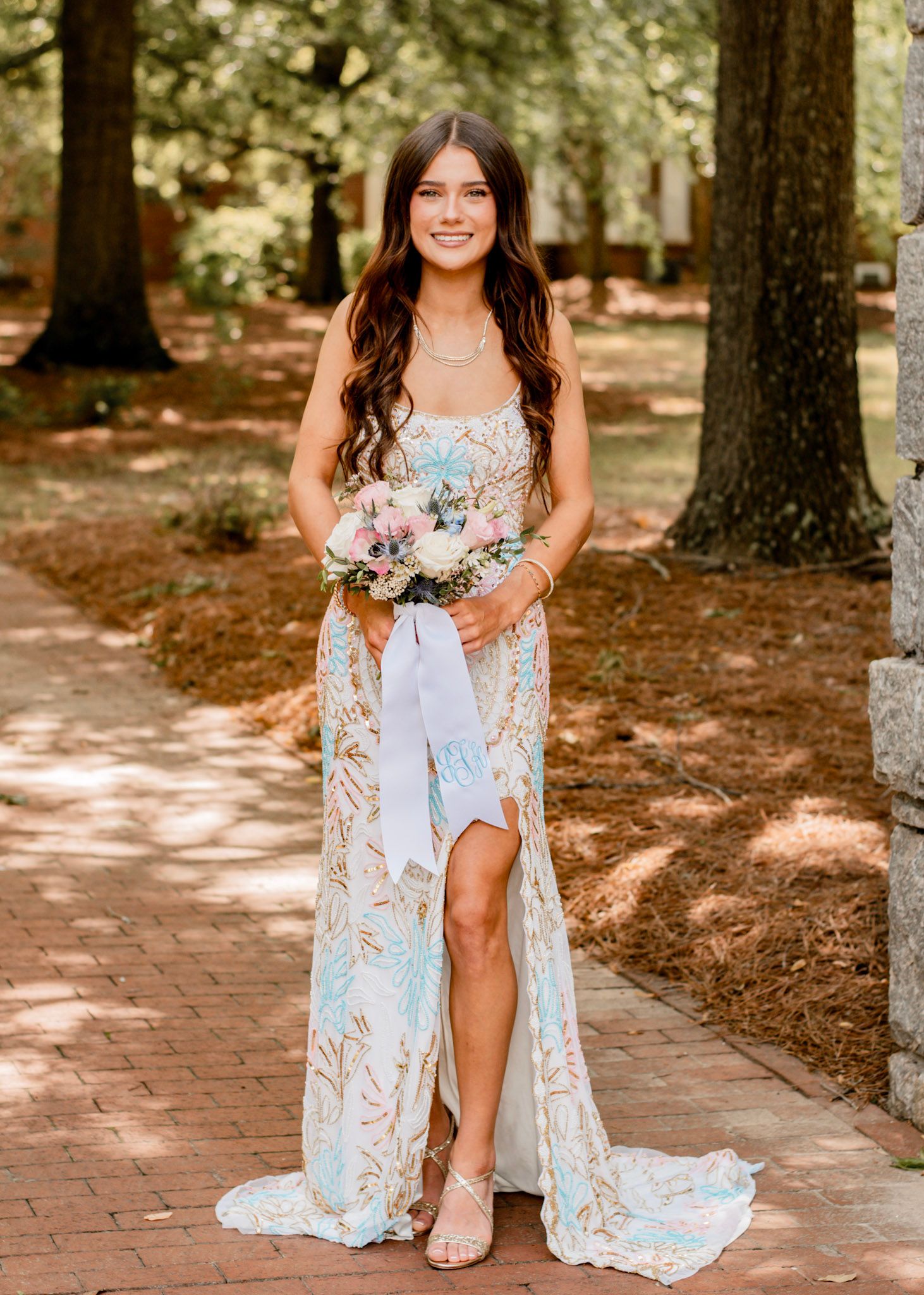 A high-school senior in a prom gown with a thigh-high slit poses on a brick pathway at Oxford College in Oxford, Georgia.