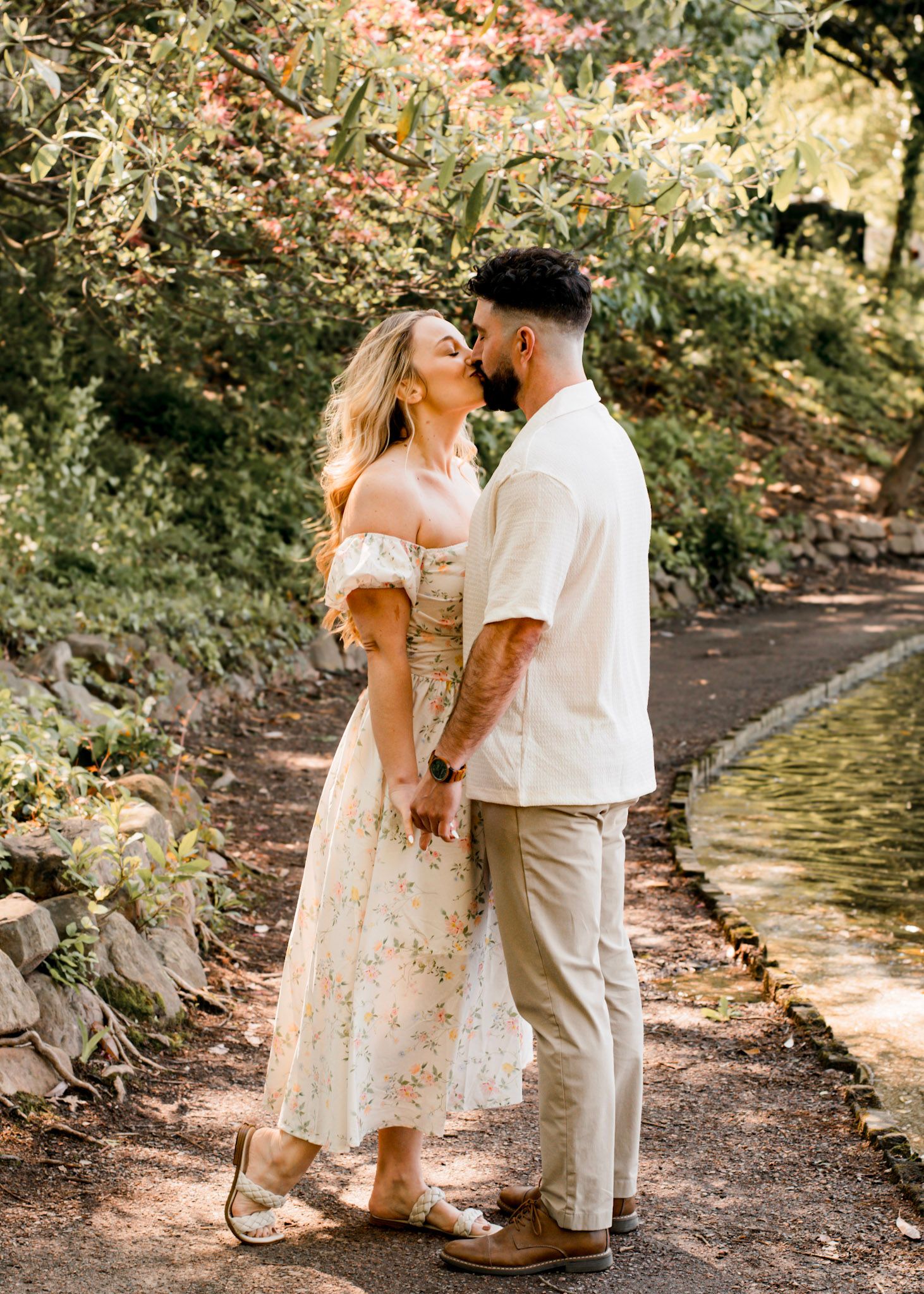 A romantic couple shares intimate moments along a wooded creek path in natural lighting at Piedmont Park in Atlanta, Georgia