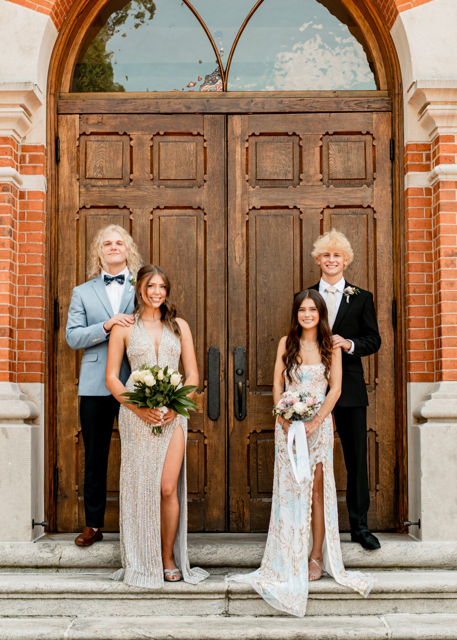Senior prom couples pose in formal attire against historic brick  doors at Oxford College in Oxford, Georgia.