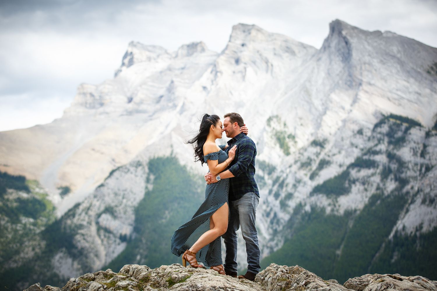 A romantic couple embraces against a backdrop of majestic  mountain peaks at Minnewanka Lake in Banff. Alberta. Banff National Park.