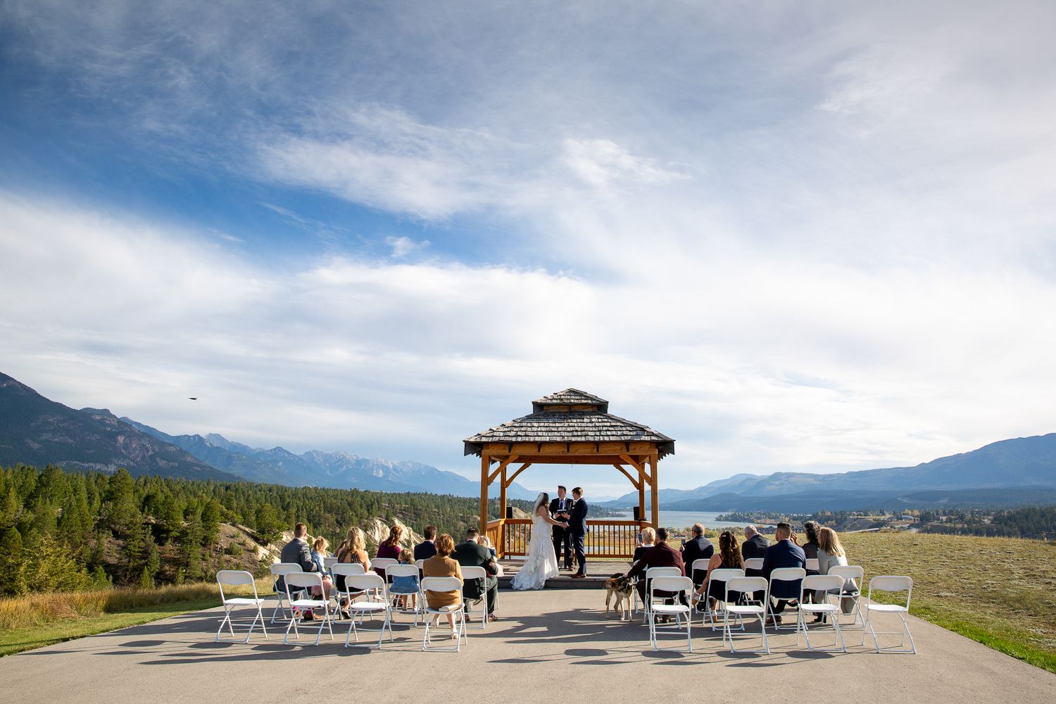 Wedding ceremony with guests seated in white chairs overlooking Columbia valley. Eagle Ranch Resort, Invermere, BC.