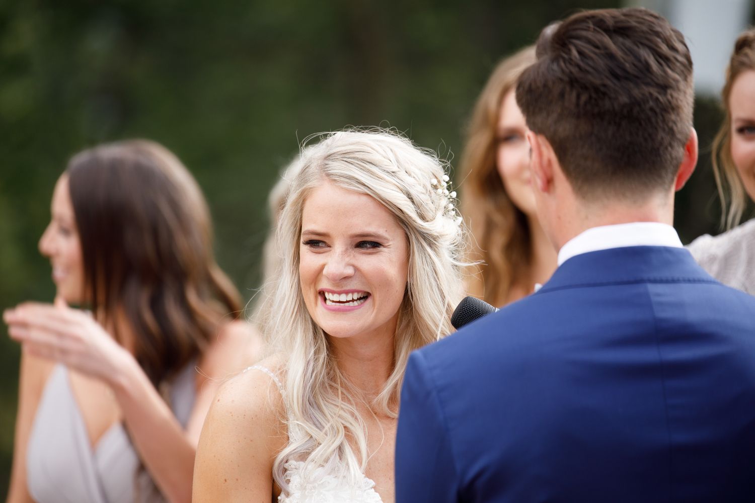 Wedding guests gathered outdoors at an elegant garden reception with natural greenery in the background.
