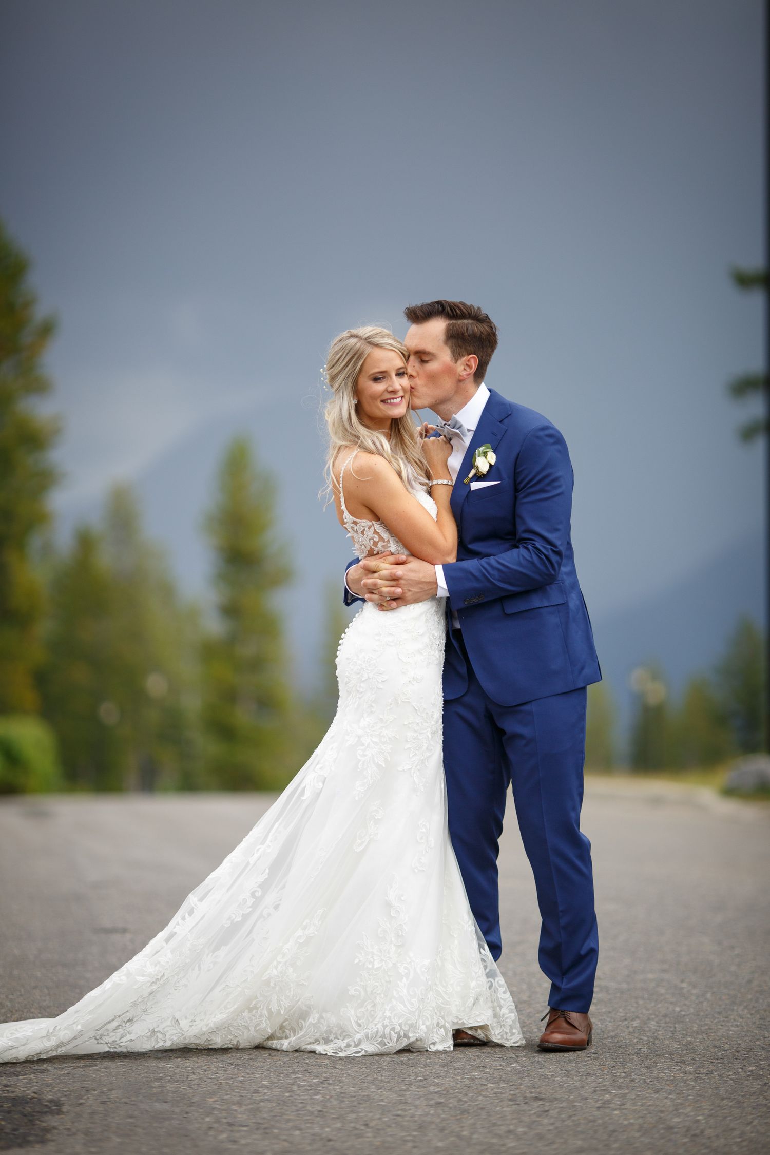 A bride and groom share an intimate moment on a mountain road in their wedding attire at Silvertip resort in Canmore.