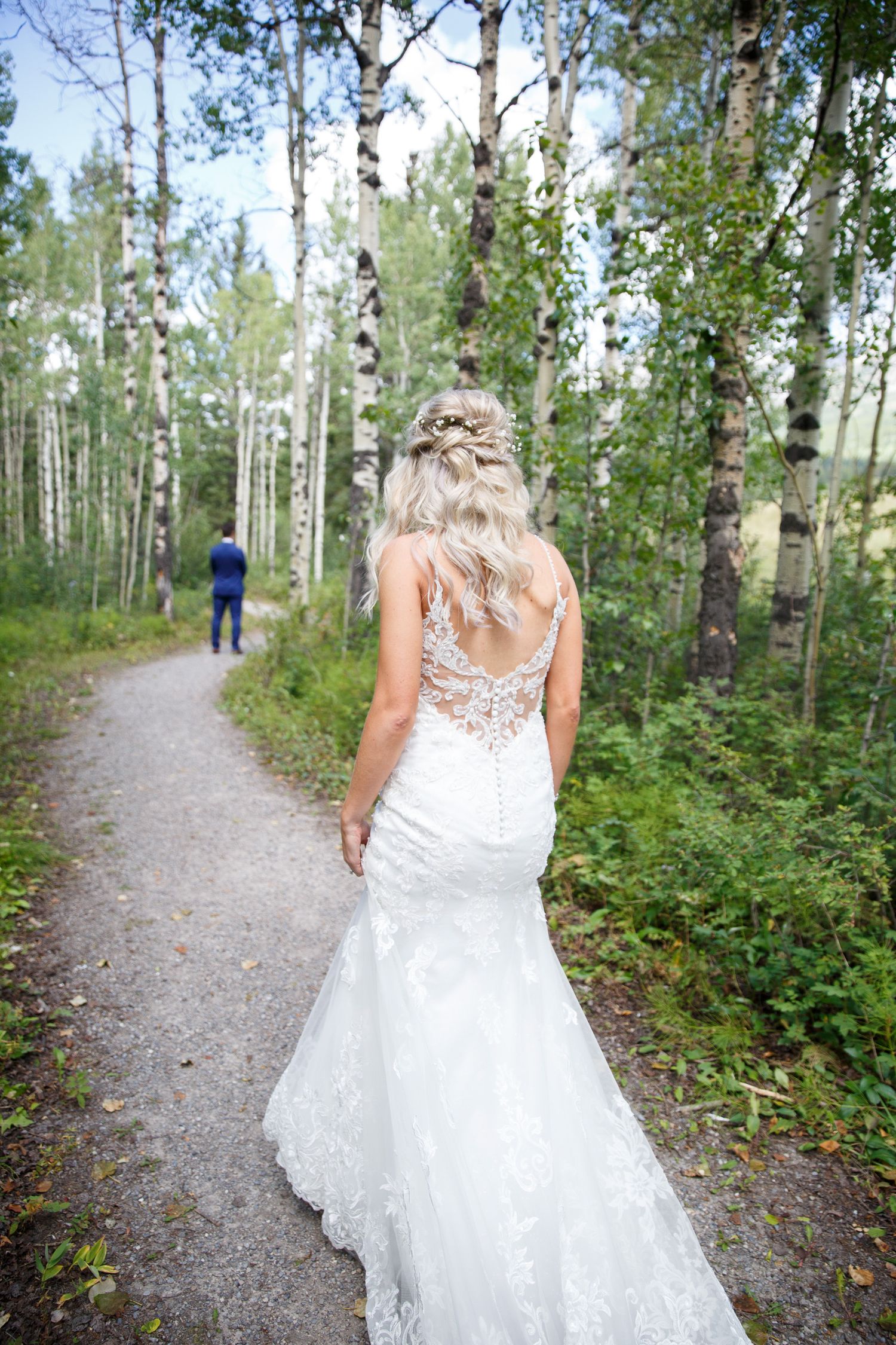 A scenic forest path through birch trees with a flowing white dress trailing behind on a peaceful nature walk.