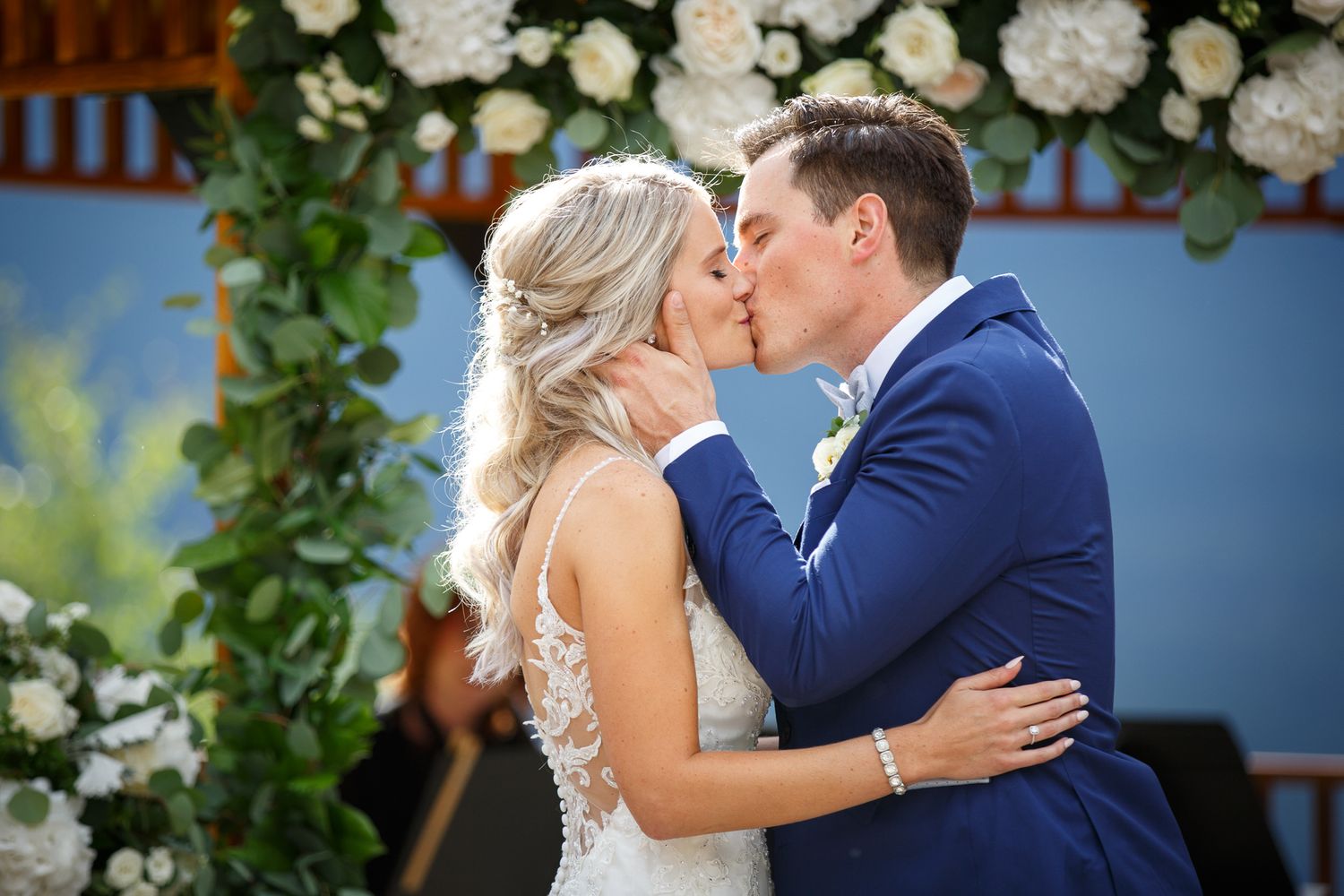 Romantic moment under floral arch with white roses and greenery decorations at Silvertip resort in Canmore.