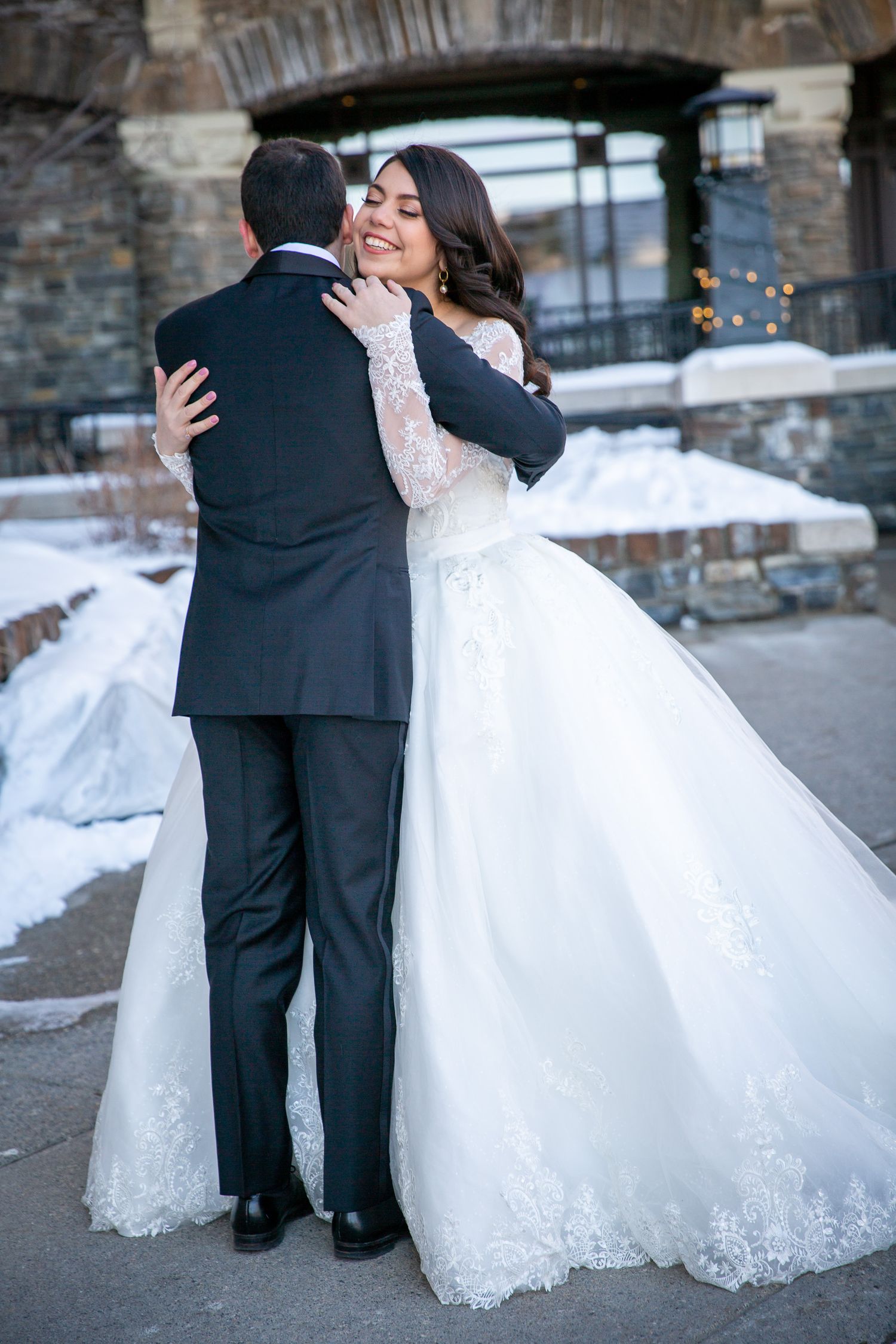 A romantic winter wedding photo series showing a couple in formal attire embracing against a snowy backdrop. Fairmont Banff Springs Hotel