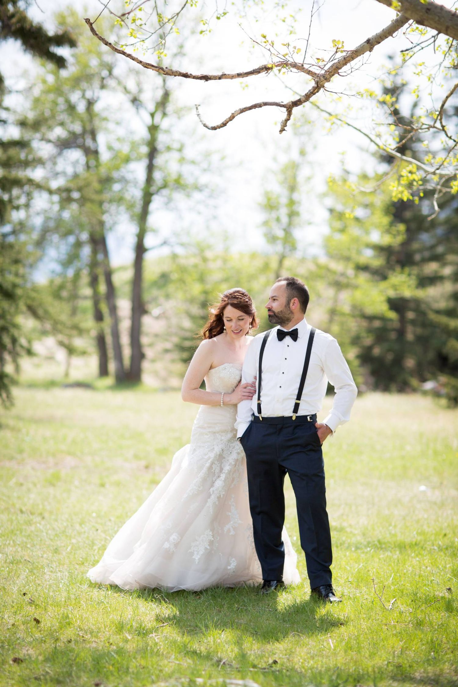 A playful wedding photo sequence in a sunny meadow with pine trees in the background. Cascade Pond day use area in Banff National Park.