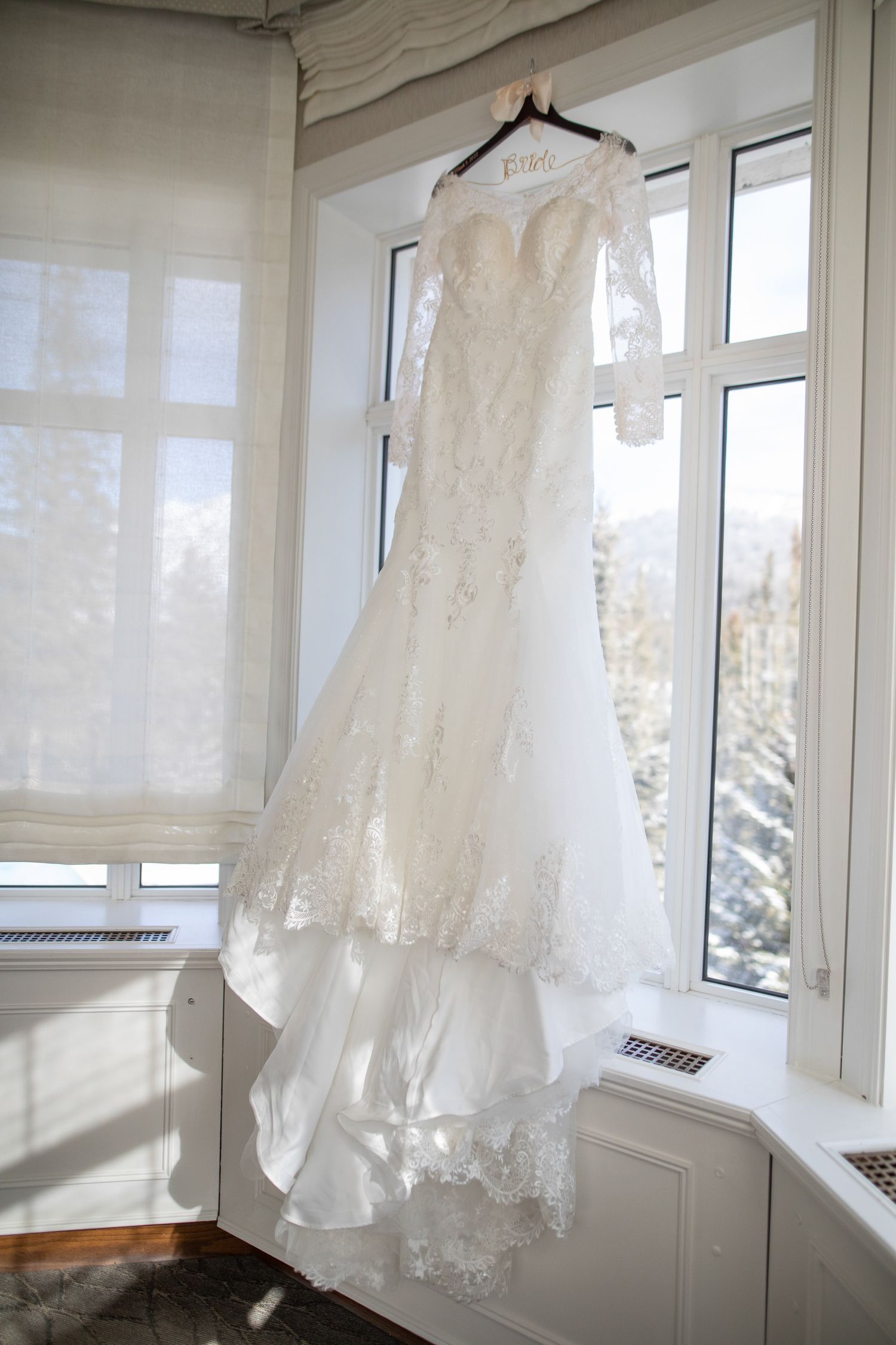 White lace wedding dresses and gowns hanging in a bright sunlit room with large windows.Fairmont Banff Springs Hotel