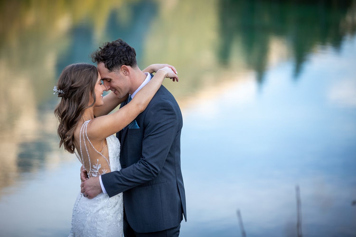 A romantic couple embraces during their wedding photoshoot in a dreamy outdoor setting with soft lighting at Silvertip resort in Canmore, AB