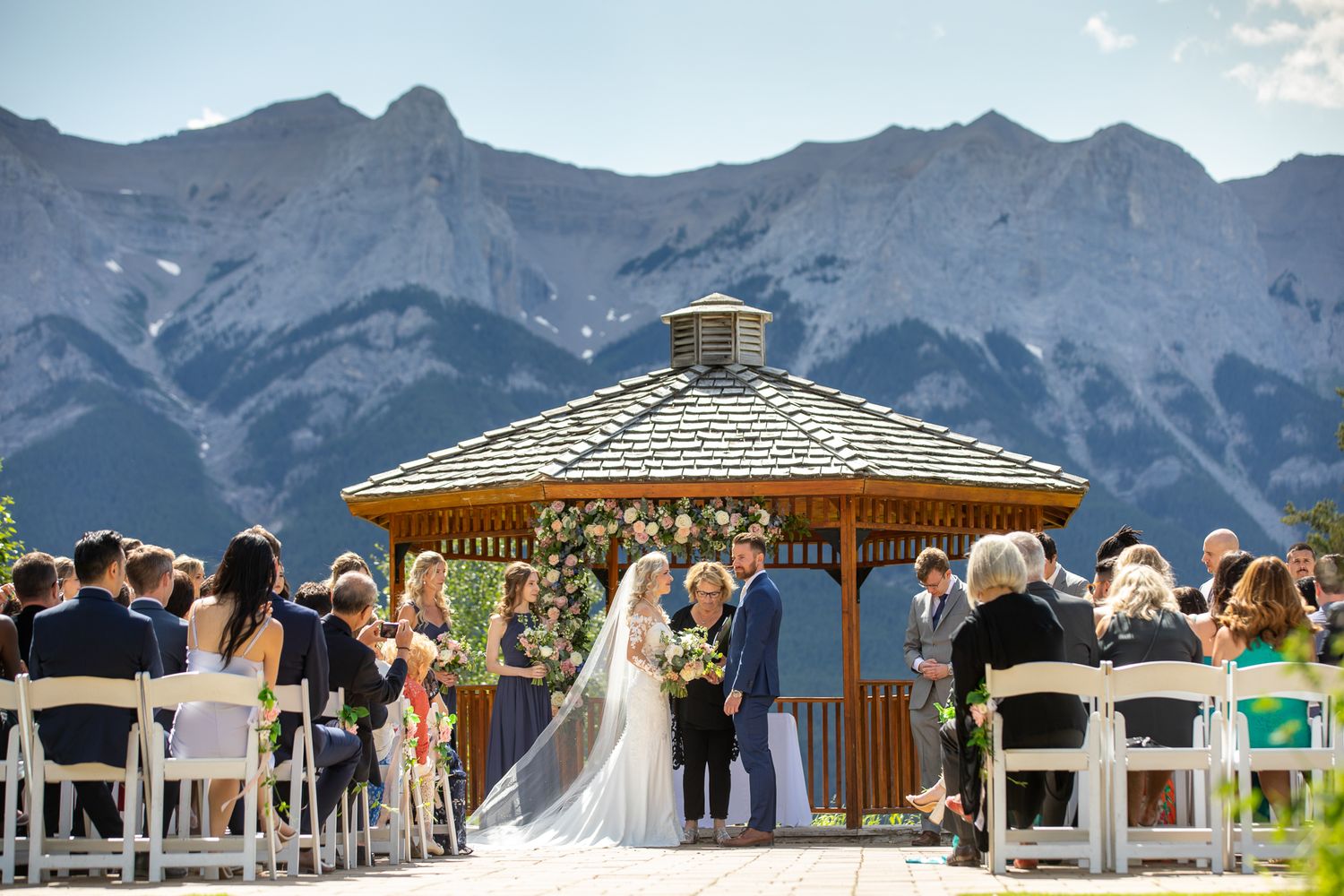 Outdoor wedding ceremony at  the Silvertip gazebo with stunning Rocky Mountain backdrop, bride and groom exchanging vows with seated guests.