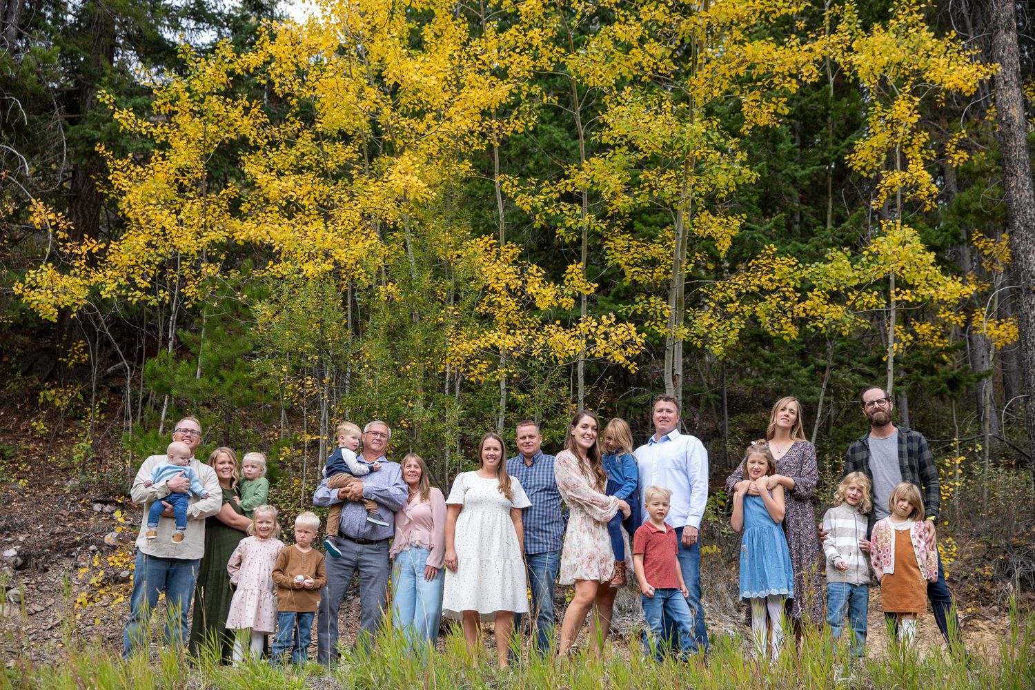 A group of people standing in a line outdoors with vibrant yellow autumn foliage in the background at Grey Wolf in Panorama, BC.
