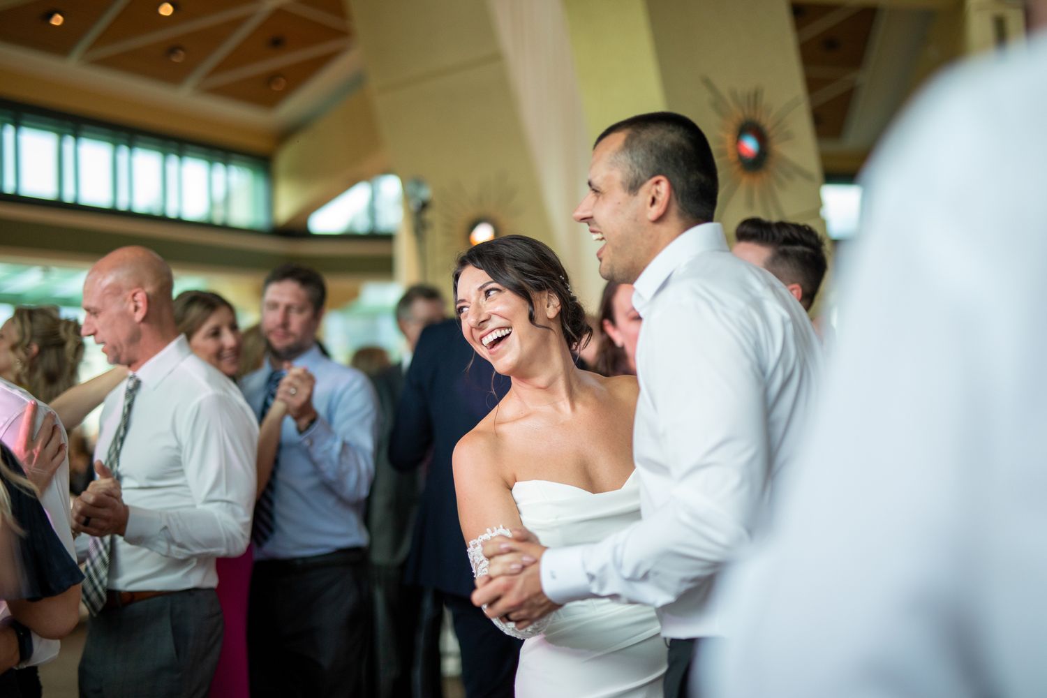 Wedding guests share joyful laughter during an indoor reception celebration at Fairmont Banff Springs golf course venue in Banff, Alberta.
