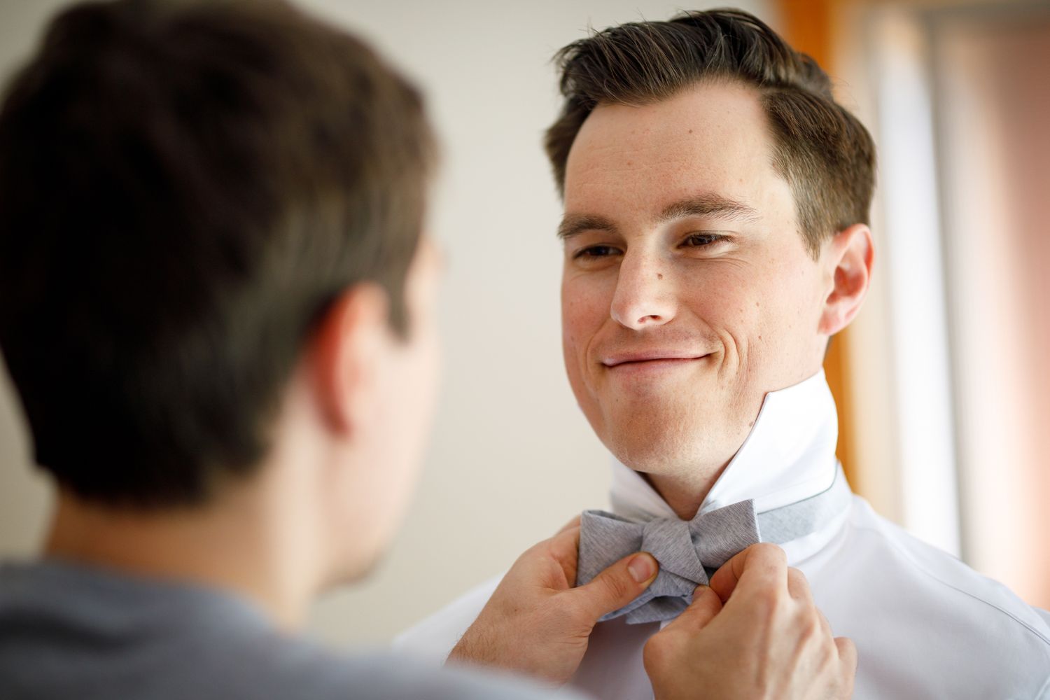 A groom gets his bow tie adjusted by a groomsman at Solara resort in Canmore.