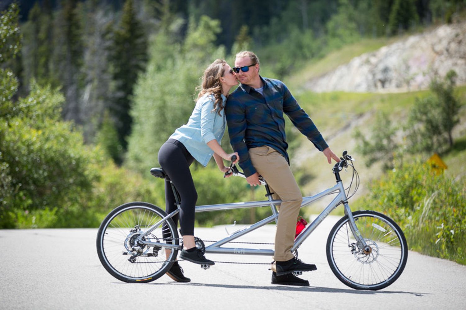 A person riding a unique low-riding bicycle with extended front forks through a scenic mountain landscape in Banff.