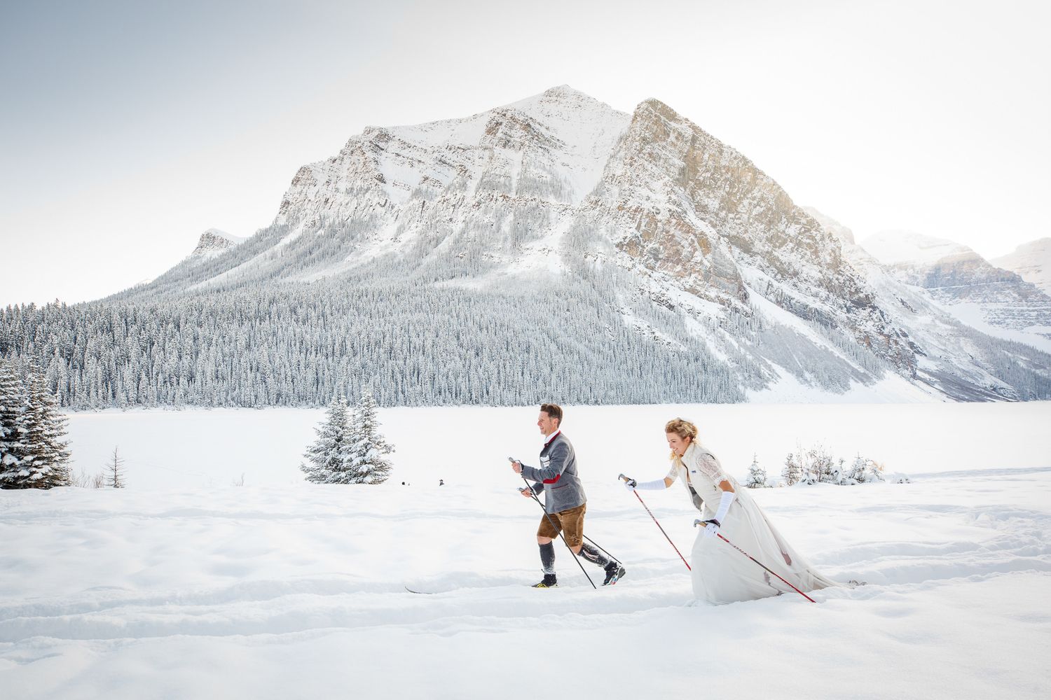 Skiers traverse snowy mountain slopes against dramatic winter landscapes at Lake Louise in the Canadian Rockies.