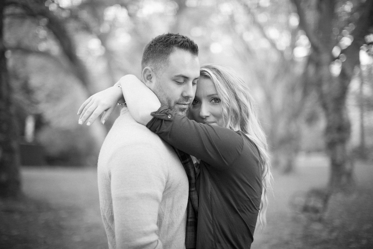 A romantic black and white photo sequence shows a couple embracing outdoors in a natural setting of Stanley Park in Vancouver, BC