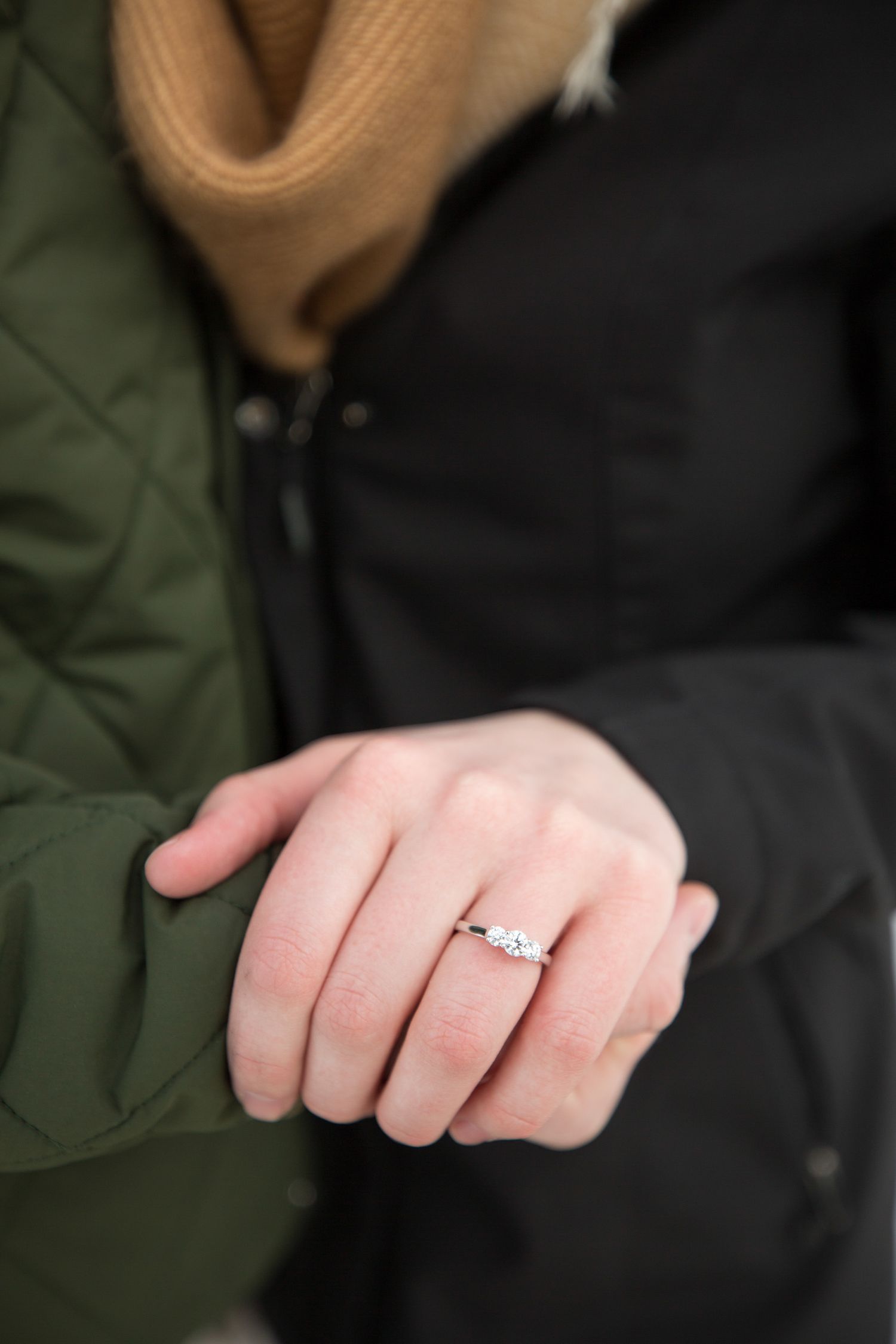 Newly engaged couple showing rings at Lake Minnewanka in  Banff in the background