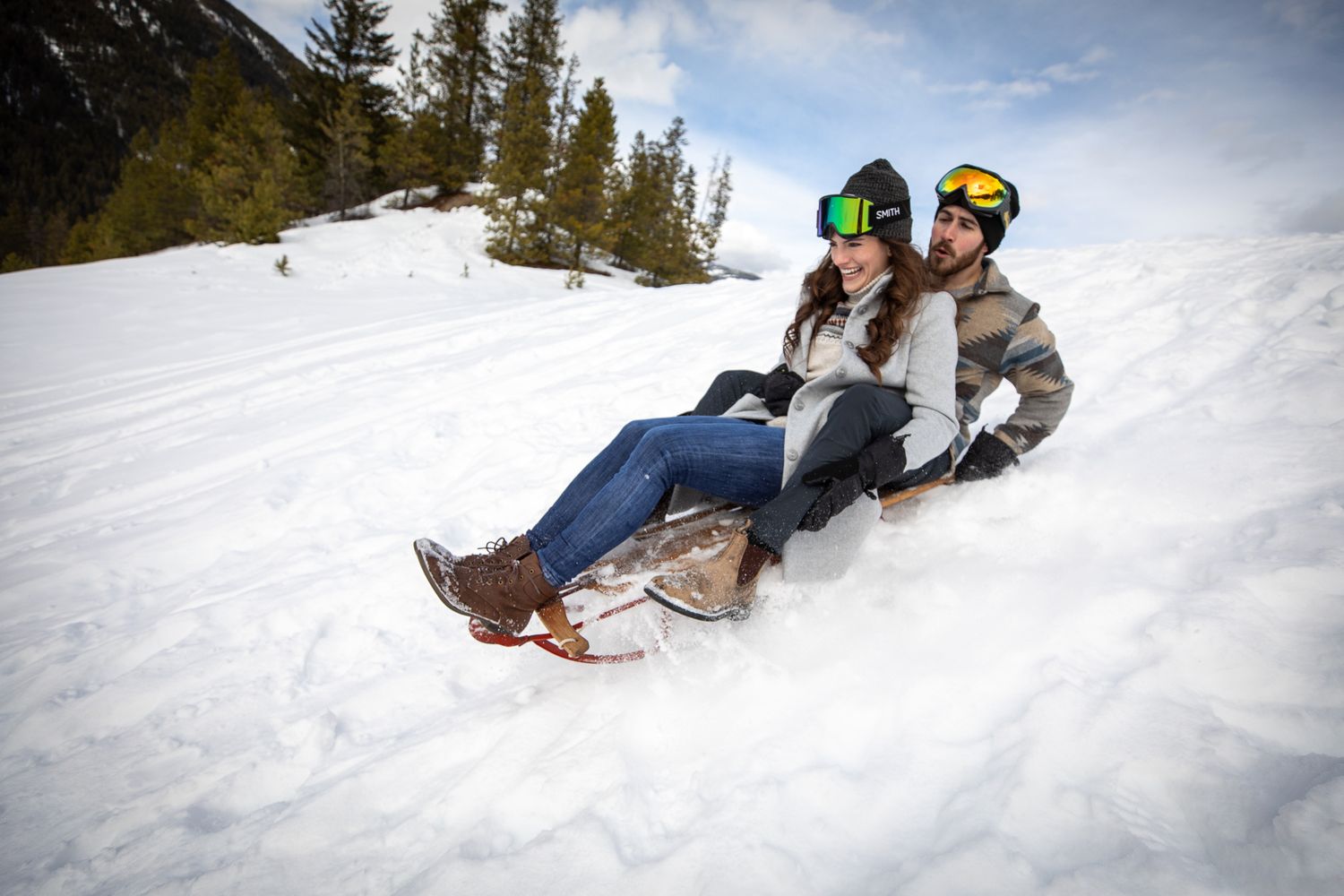 Group of people sledding down a snowy hill during winter activities at Grey Wolf Panorama, BC