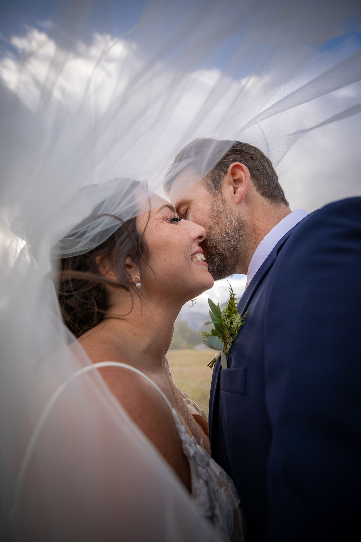 Intimate wedding moment captured under flowing veil with mountain backdrop in Banff, Alberta