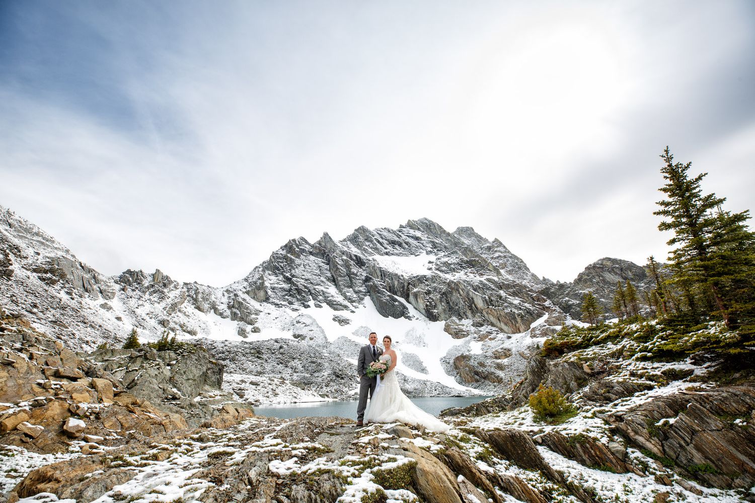 Wedding couple standing with a majestic mountain background wilderness of Kimberley BC
