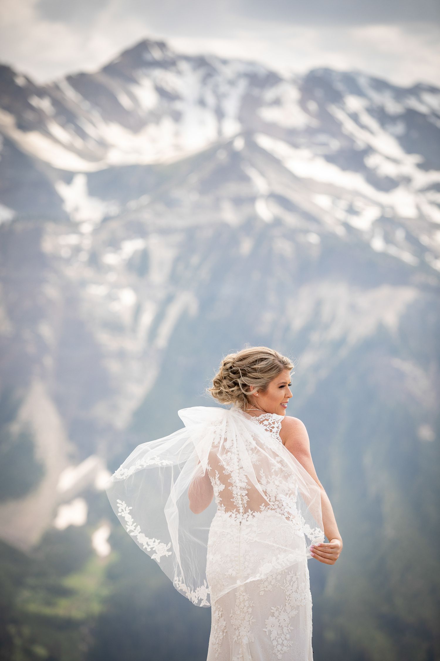 Bride's veil flows dramatically against majestic snow-capped mountain backdrop at Eagle Eye restaurant at Kicking Horse resort, Golden, BC