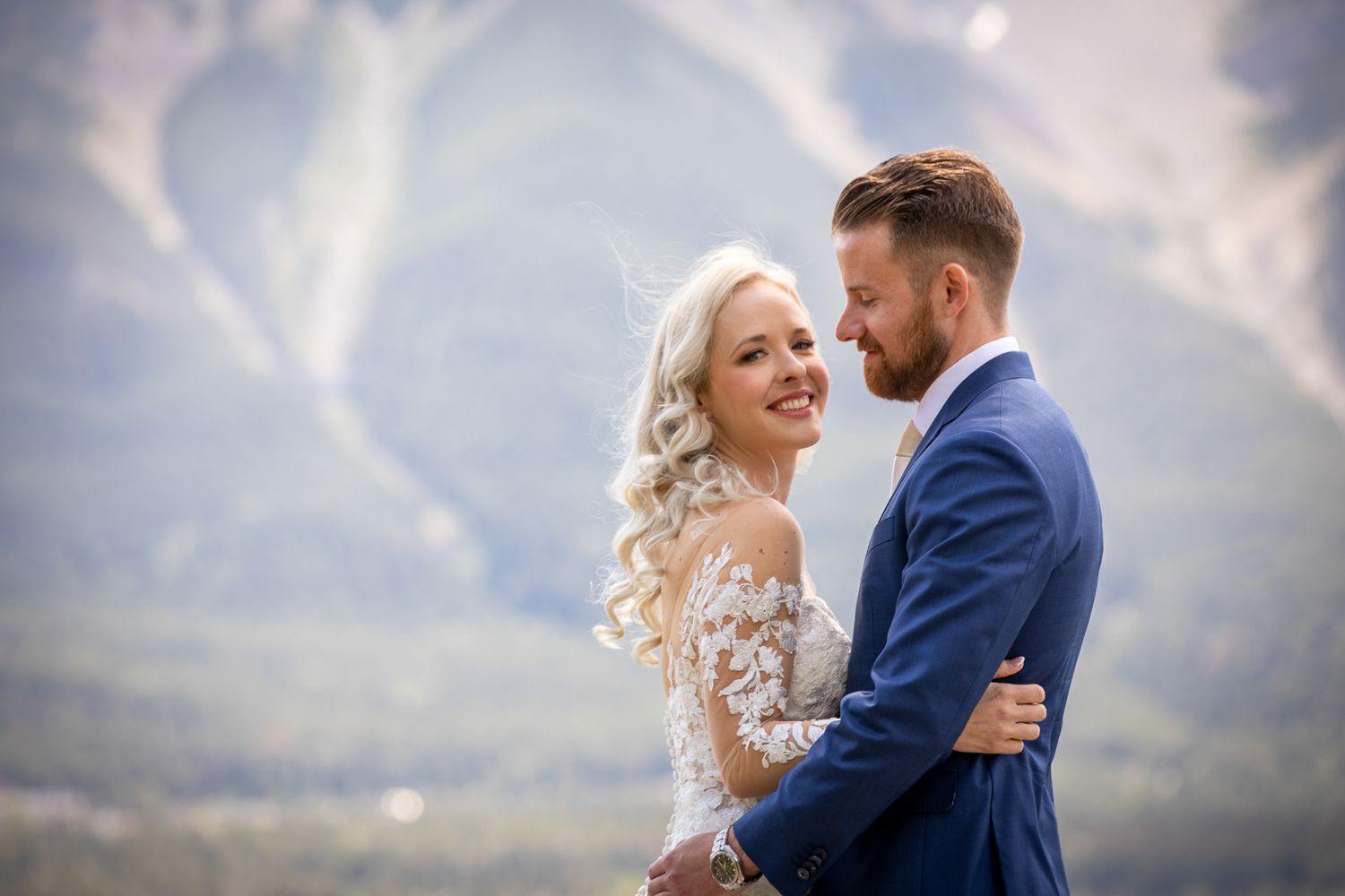 A bride and groom embrace romantically with stunning mountain scenery in the background on their wedding day Canmore Benchland Trail