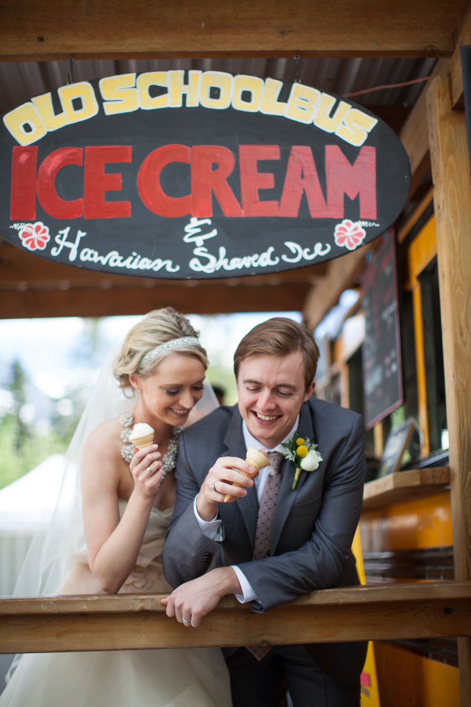 Couple laughs together while sitting in front of vintage ice cream shop signs in Canmore main street. Canmore, Alberta.