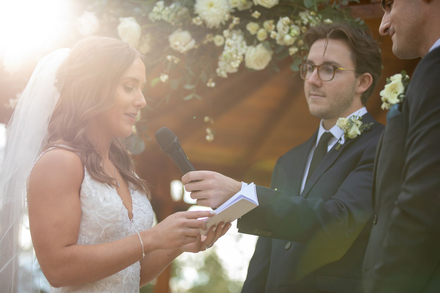 A romantic wedding couple shares an intimate moment under blooming white flowers during a outdoor ceremony at Silvertip resort in Canmore.