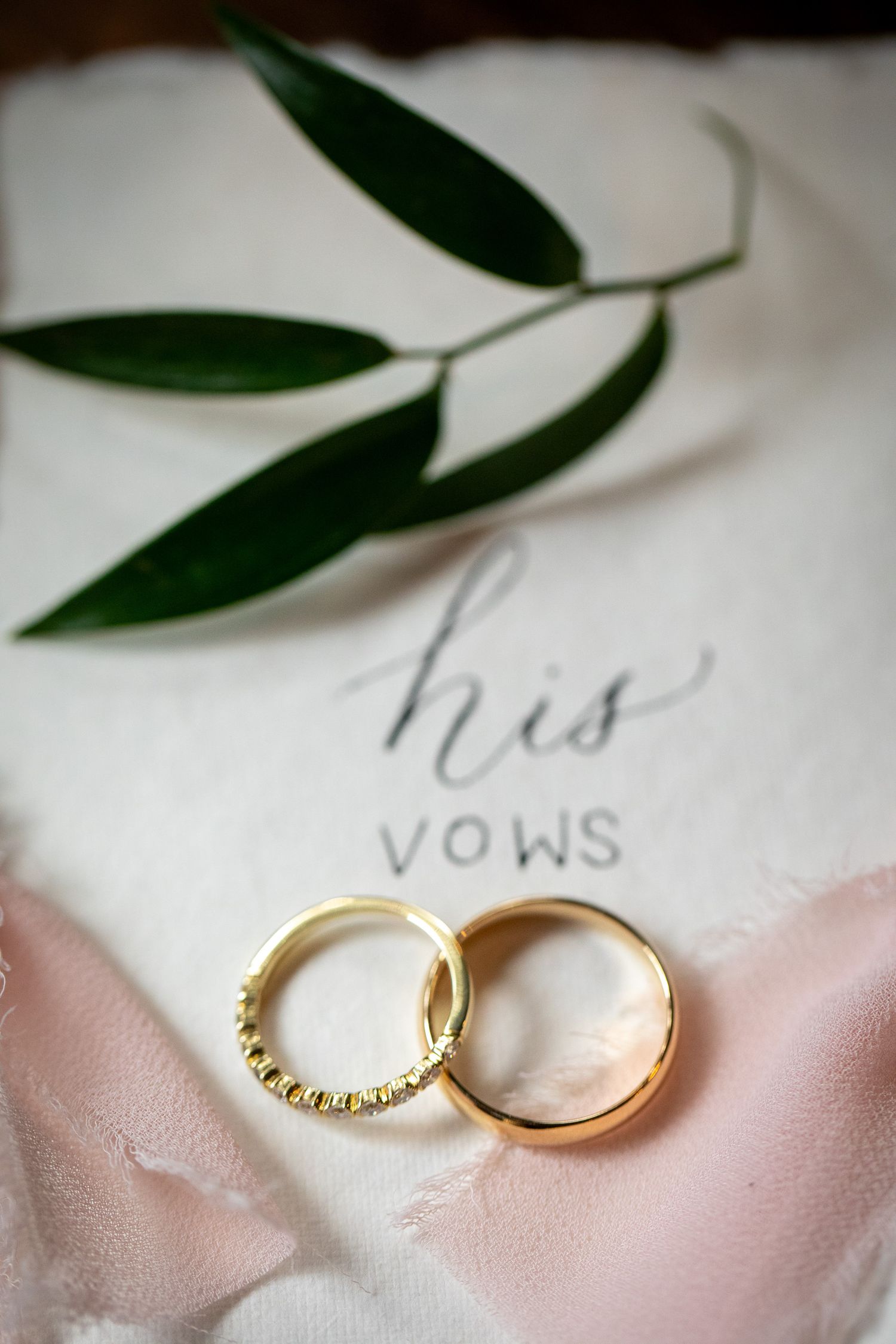 Two gold wedding rings rest on pink fabric next to handwritten vows text. Buffalo Mountain Resort, Banff.