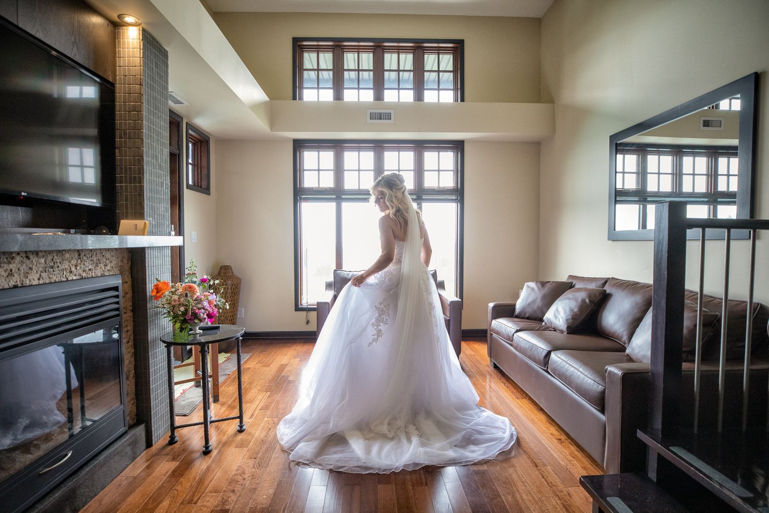 Bride in a white ball gown wedding dress standing in an elegant room with hardwood floors and a fireplace. Copperpoint resort,  Invermere.