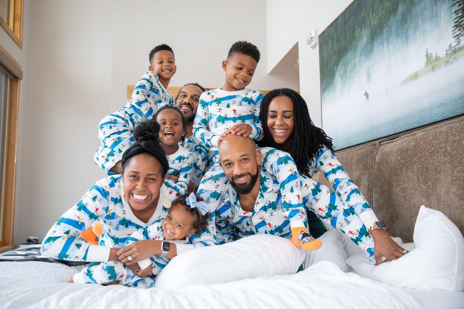 Family wearing matching blue and white tie-dye pajamas laughs together while relaxing on a cozy gray couch Canmore, AB.