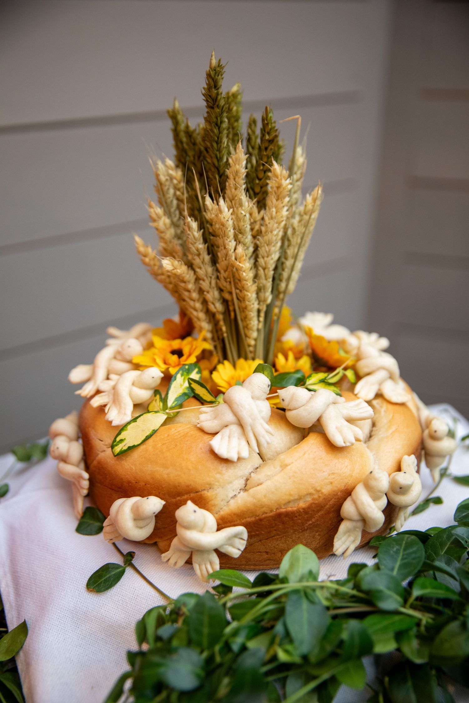 Decorative bread loaf adorned with white flowers and wheat stalks arranged in a rustic harvest style display.