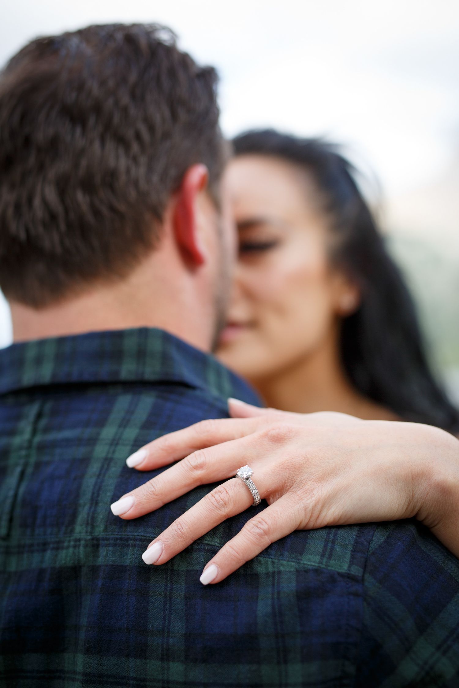 A romantic couple embracing each other tenderly, with the woman's hands on the man's back at Lake Minnewanka in Banff.