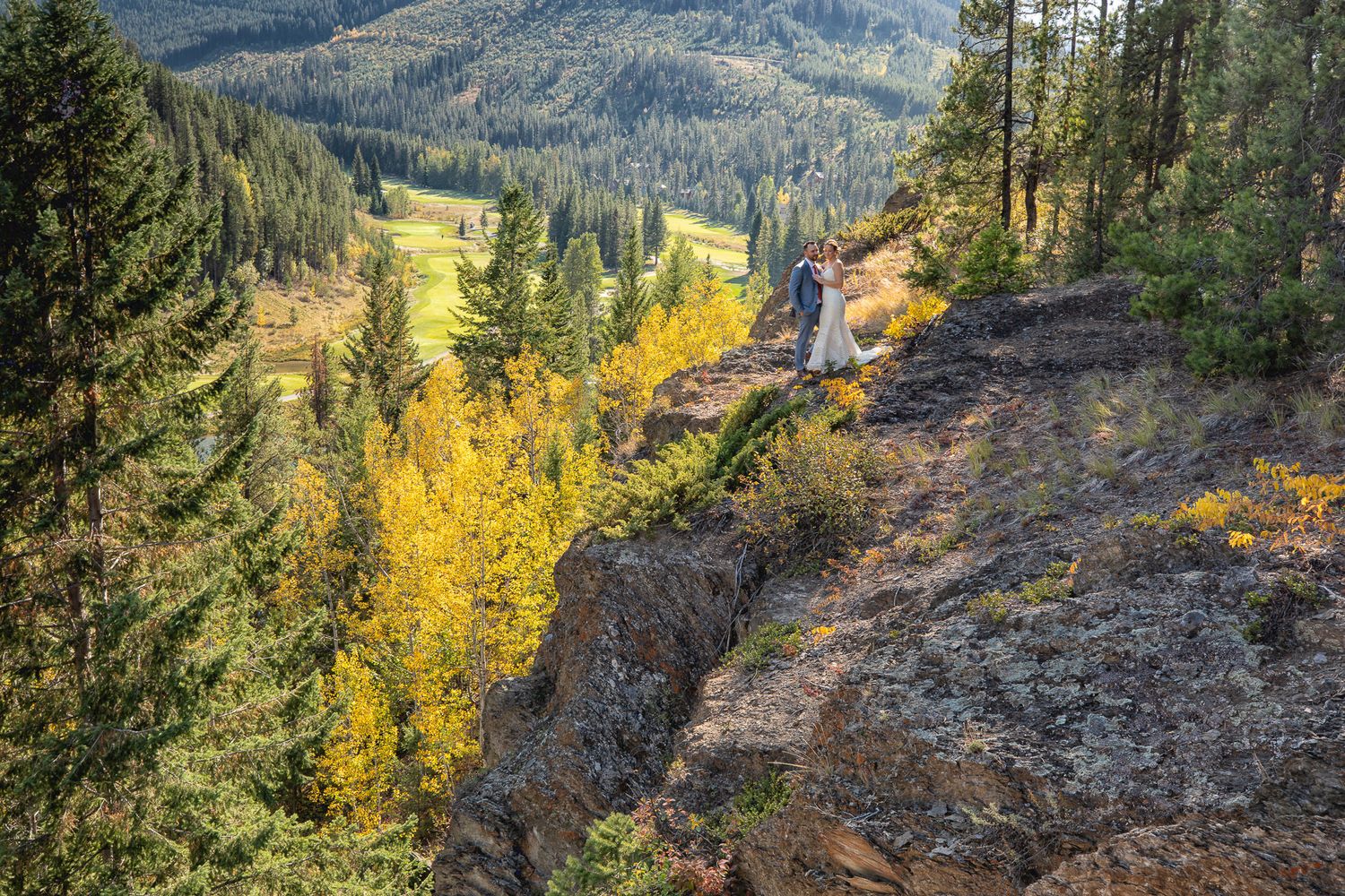 Wedding couple in a scenic mountain valley trail through autumn forest with golden aspen trees in Panorama resort in British Columbia.