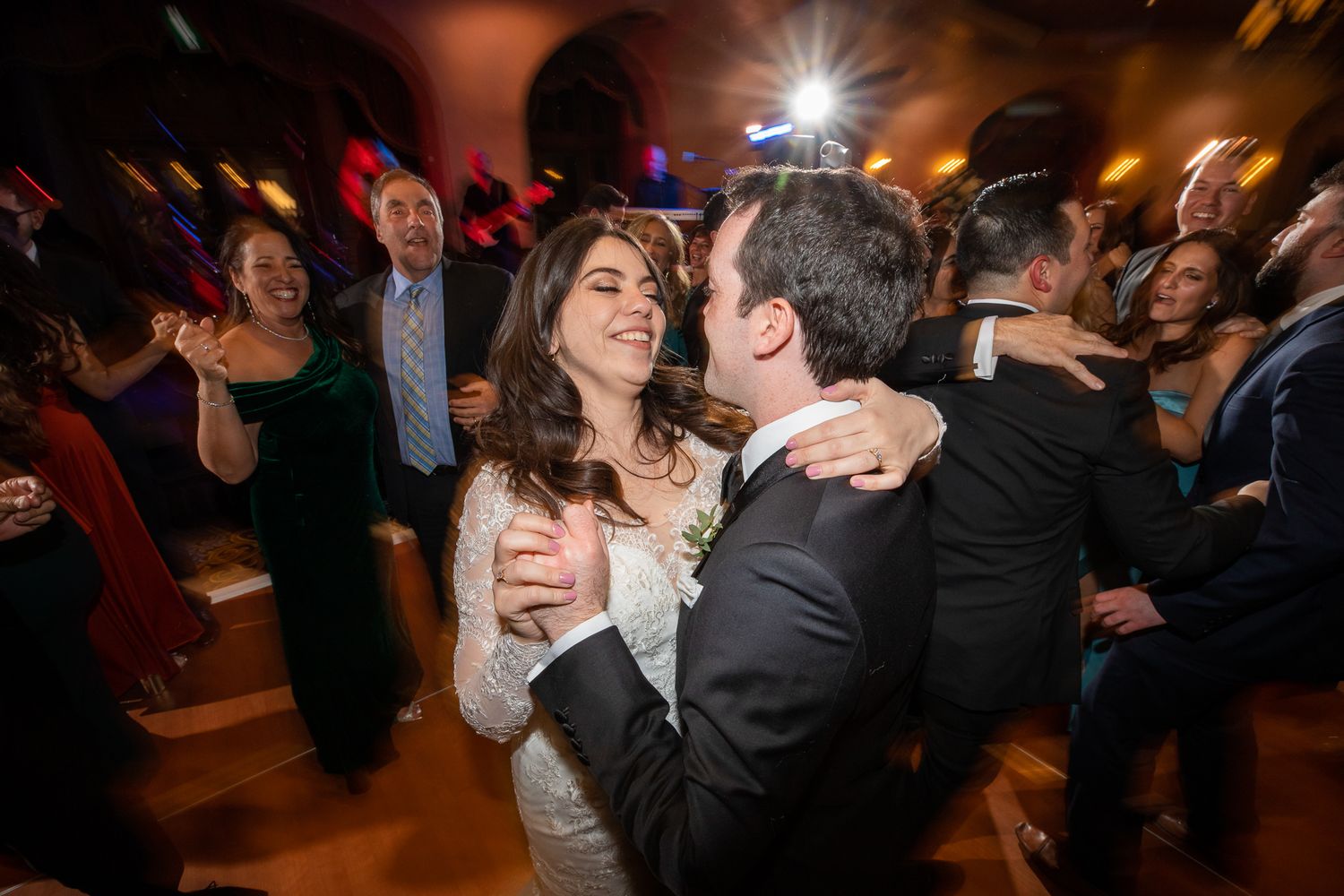 Wedding guests dance together on a dimly lit dance floor during an evening reception celebration at Alhambra room Fairmont Banff Springs.