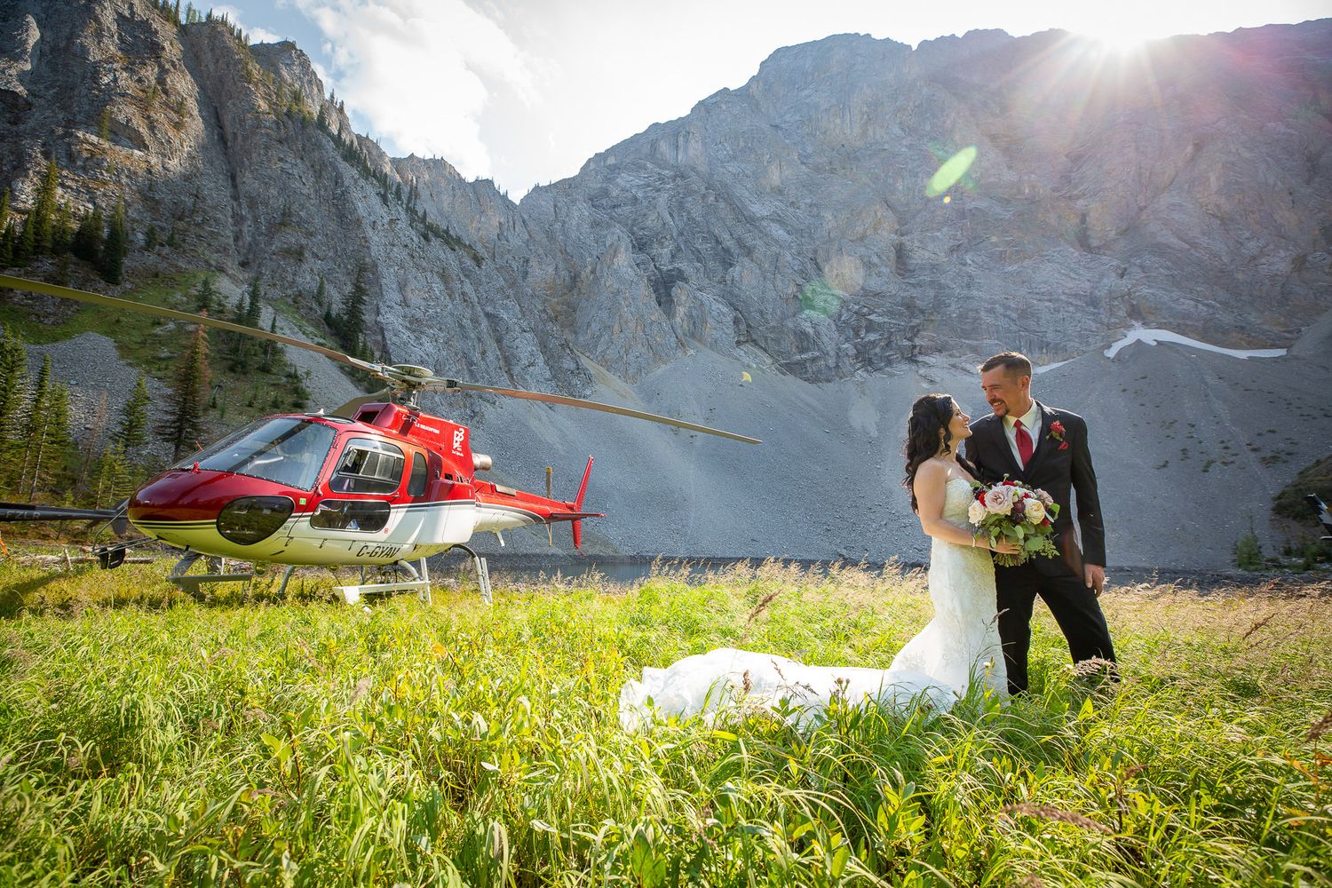 A scenic mountain helicopter wedding photoshoot with dramatic peaks and sunlight in the Canadian Rockies near Elkford, British Columbia.