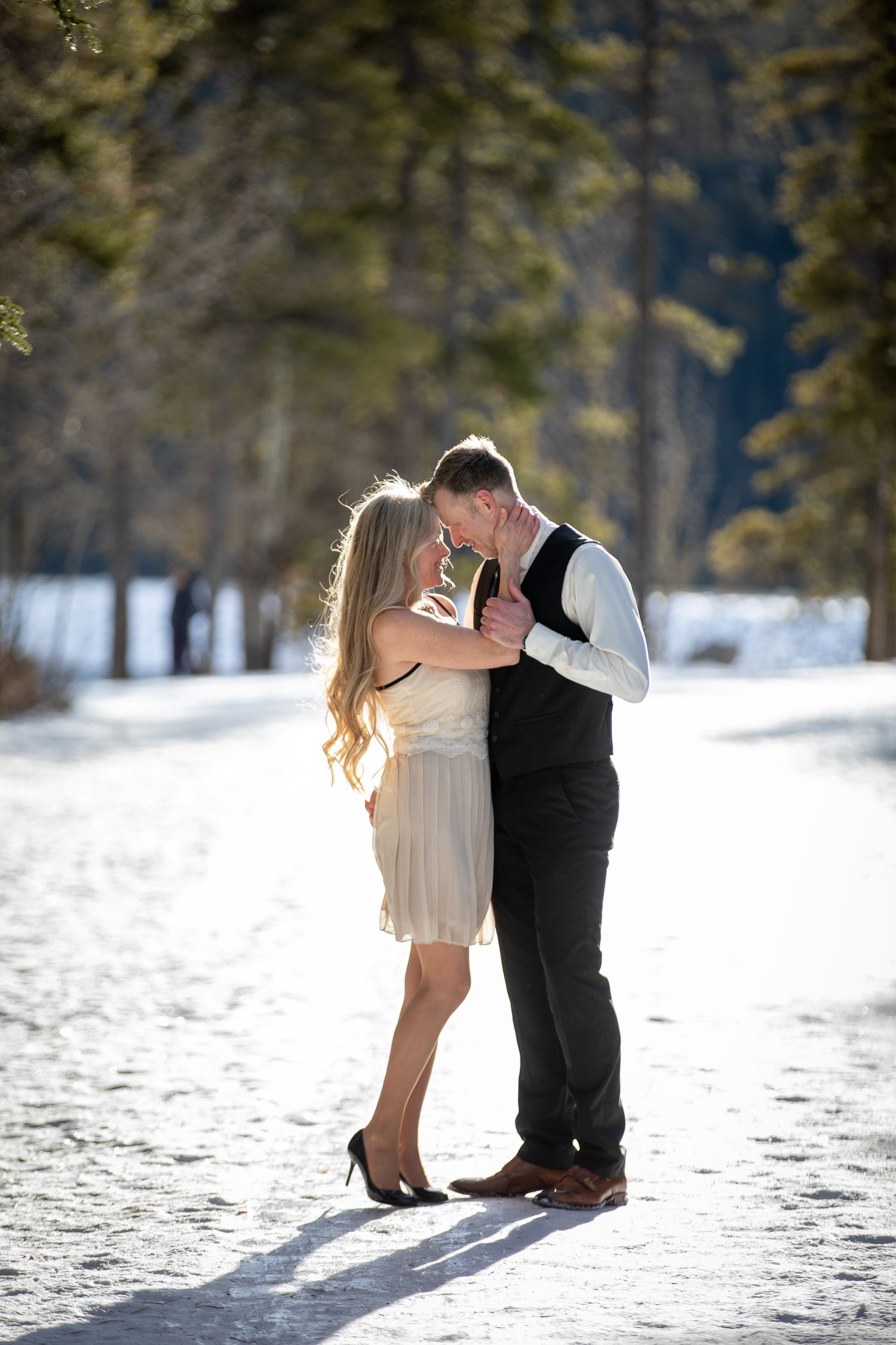 A romantic winter engagement photo series showing a couple in formal wear embracing in the snow at Lake Minnewanka.