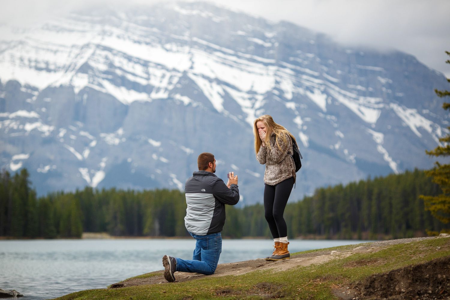 Couple captured during a surprise proposal at Two Jack Lake in Banff with the majestic Mount Rundle in the background