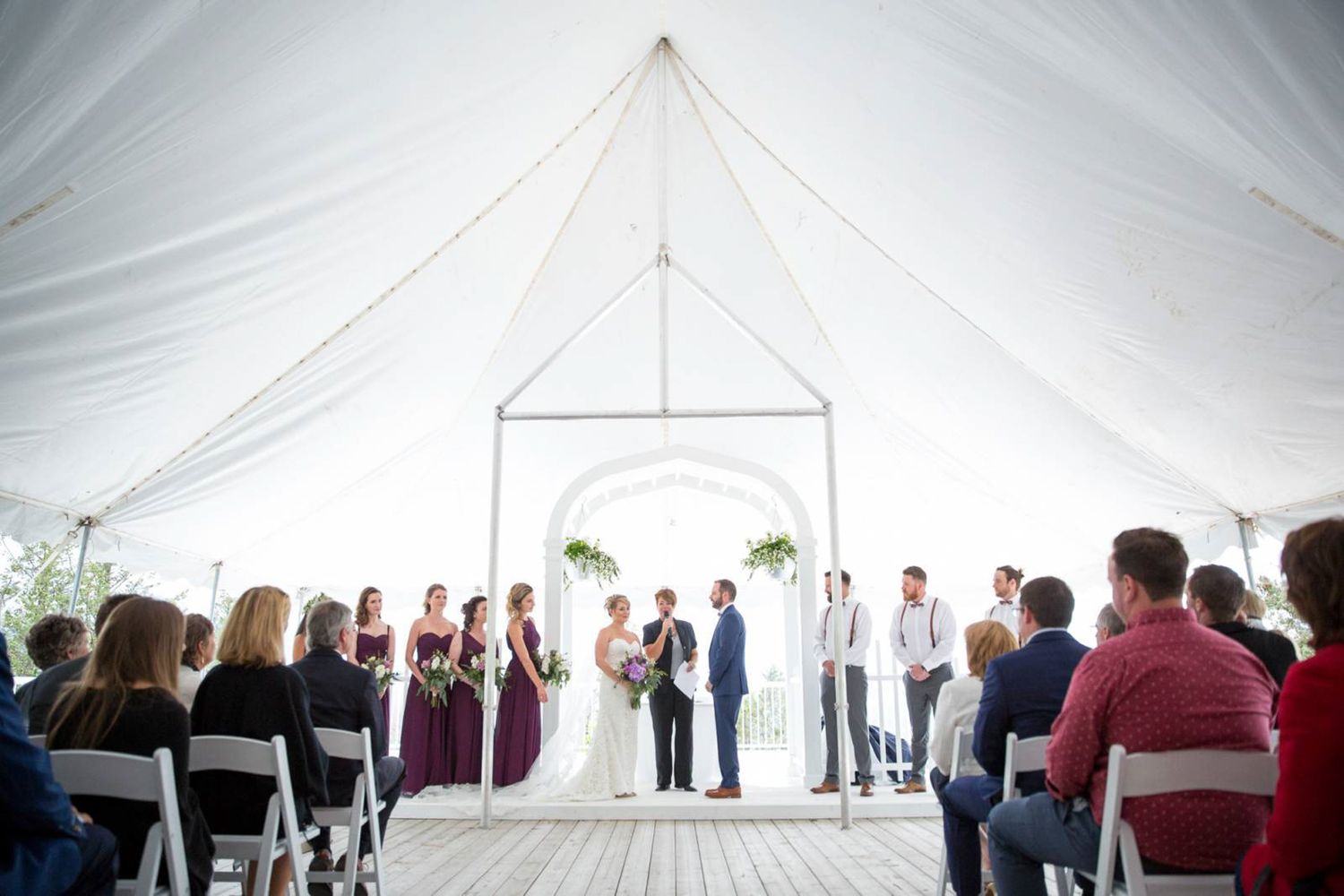 Wedding ceremony taking place under an elegant white tent with guests seated in rows watching the proceedings. Fairmont Hot Springs in BC.