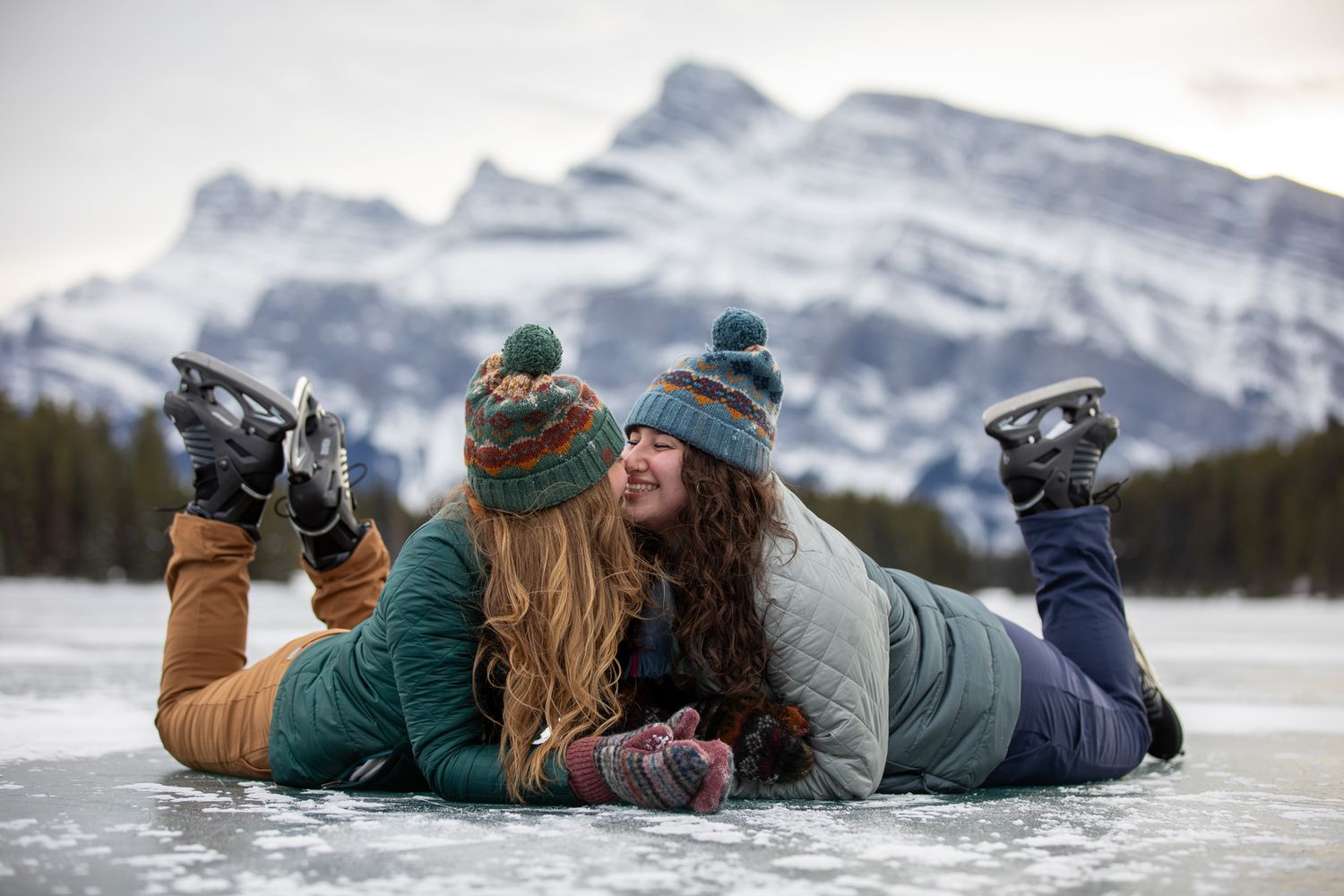 Skating Winter engagement session on frozen Two Jack lake in Banff with snow-capped mountains in background. Banff National Park.