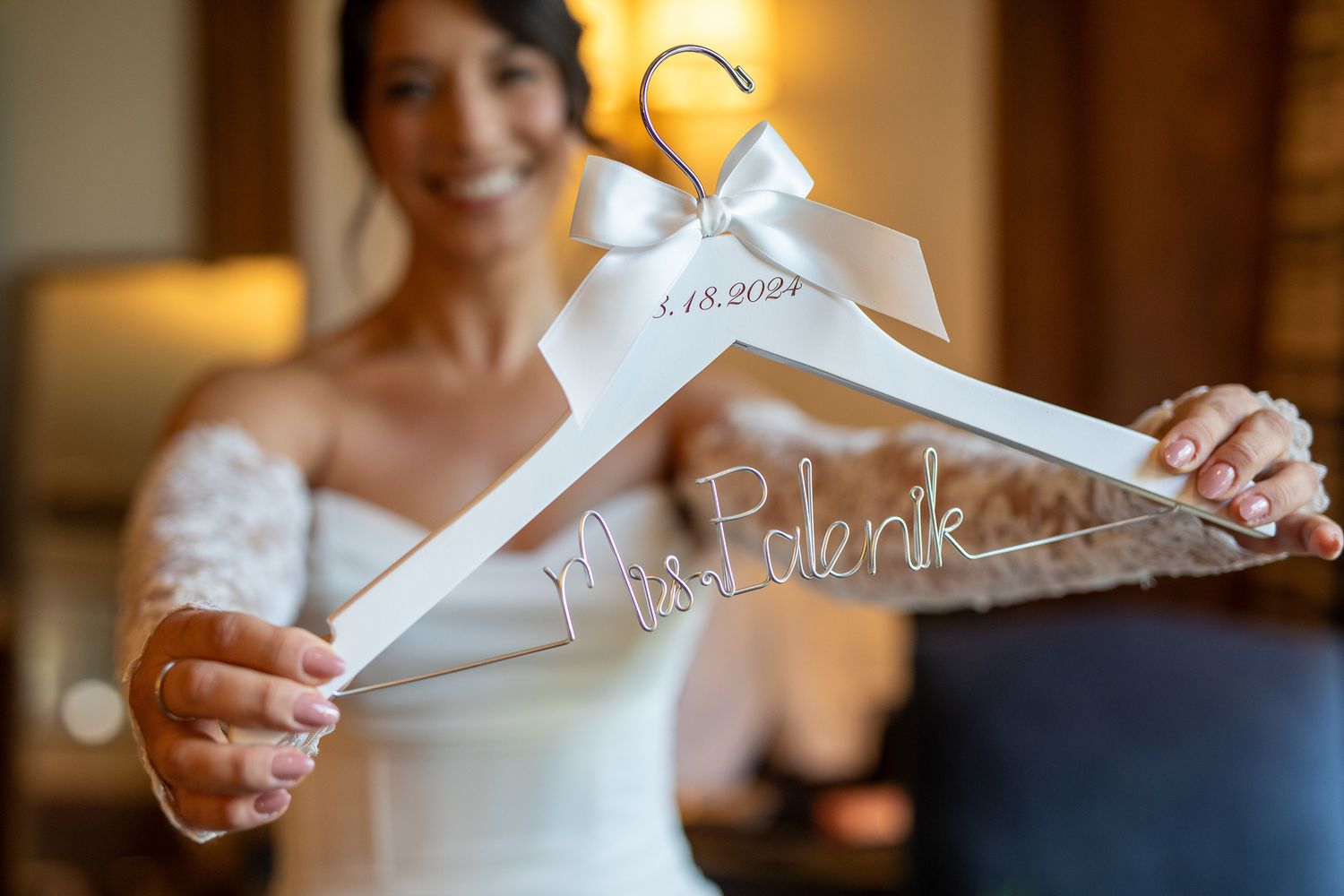 A white personalized wedding dress hanger being held up by a bride in a warmly lit room at Fairmont Banff Springs hotel in Banff, Alberta.