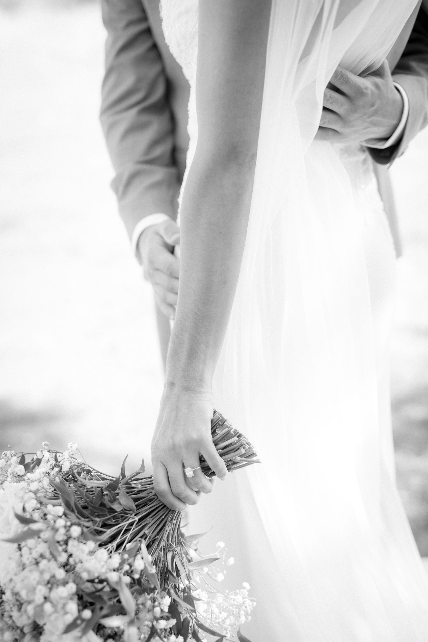 A black and white close-up of hands holding a delicate bouquet of baby's breath flowers. Silvertip resort in Canmore, Alberta.