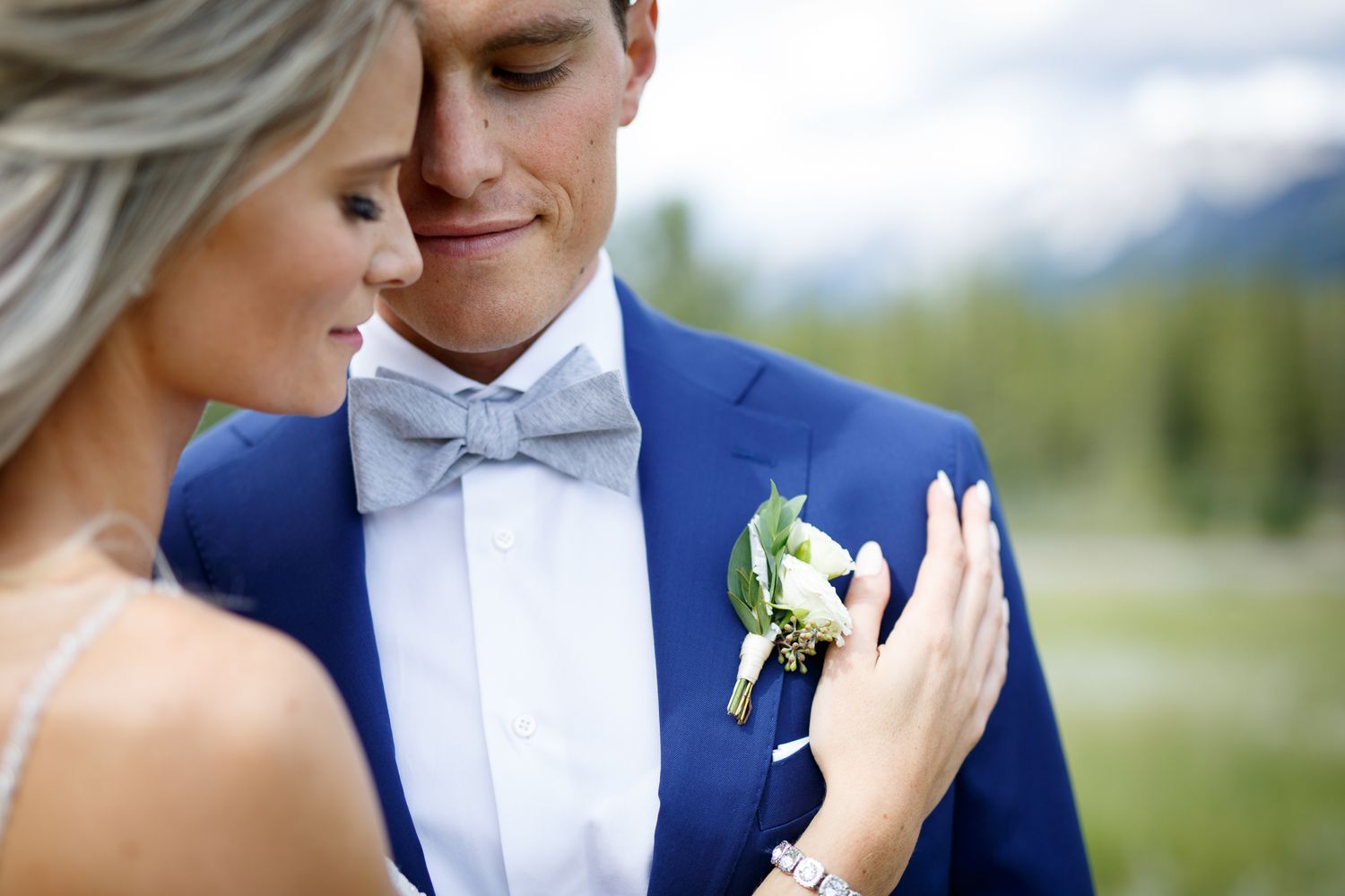 A romantic wedding couple embraces outdoors with scenic mountain views in the background Quarry lake park in Canmore.