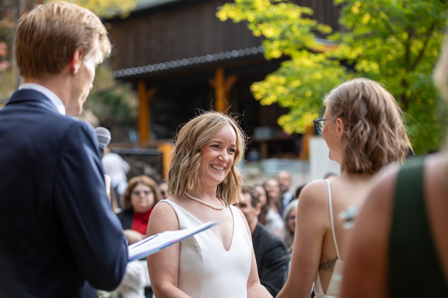 A group of wedding guests gather outdoors for a casual reception celebration in a garden setting. Earl Grey Lodge Panorama BC