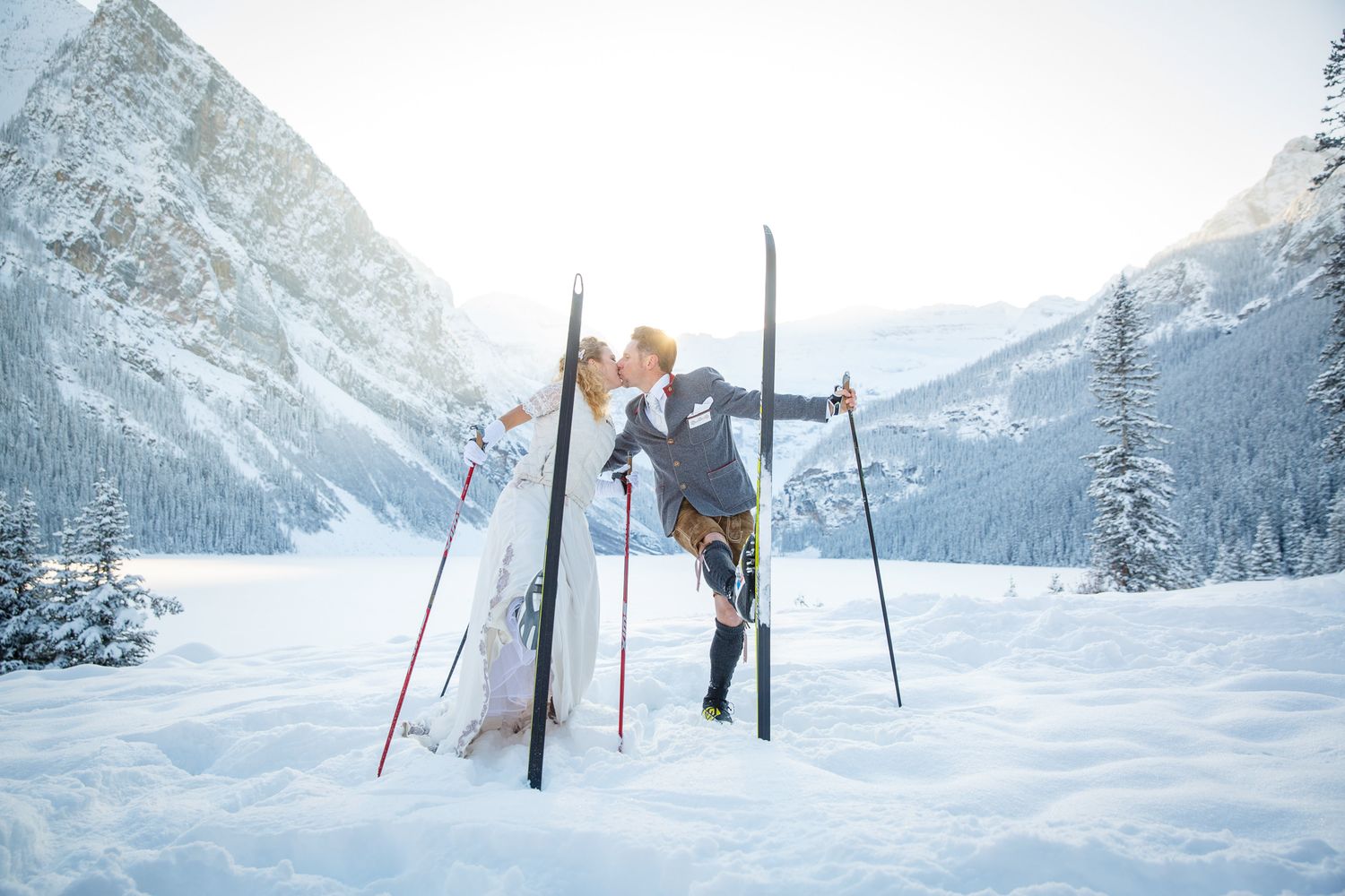 A wedding couple playing with skis as props for a photo shoot at Lake Louise